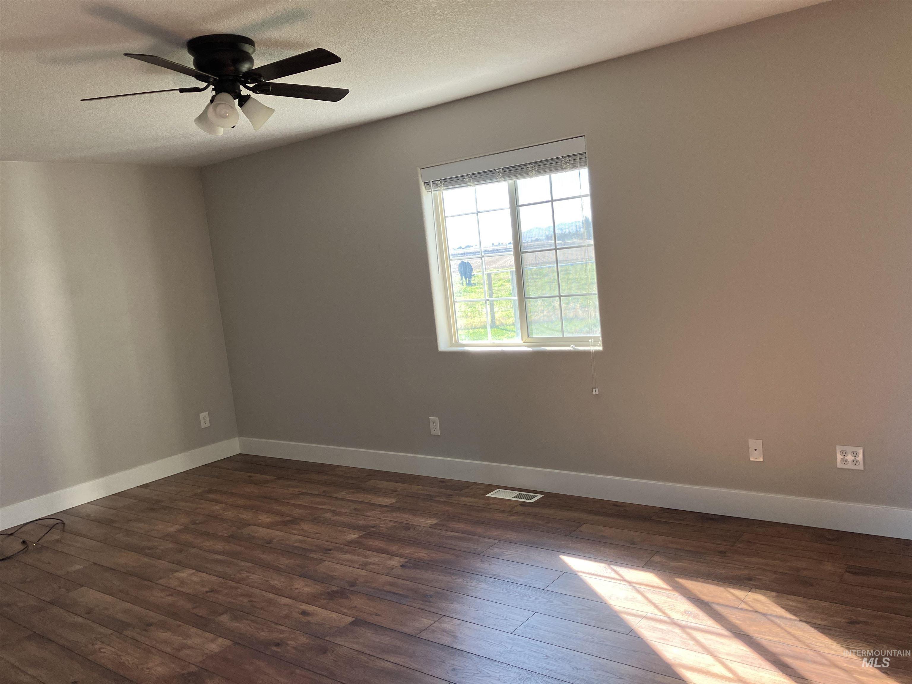Unfurnished room with dark wood finished floors, a textured ceiling, and a ceiling fan