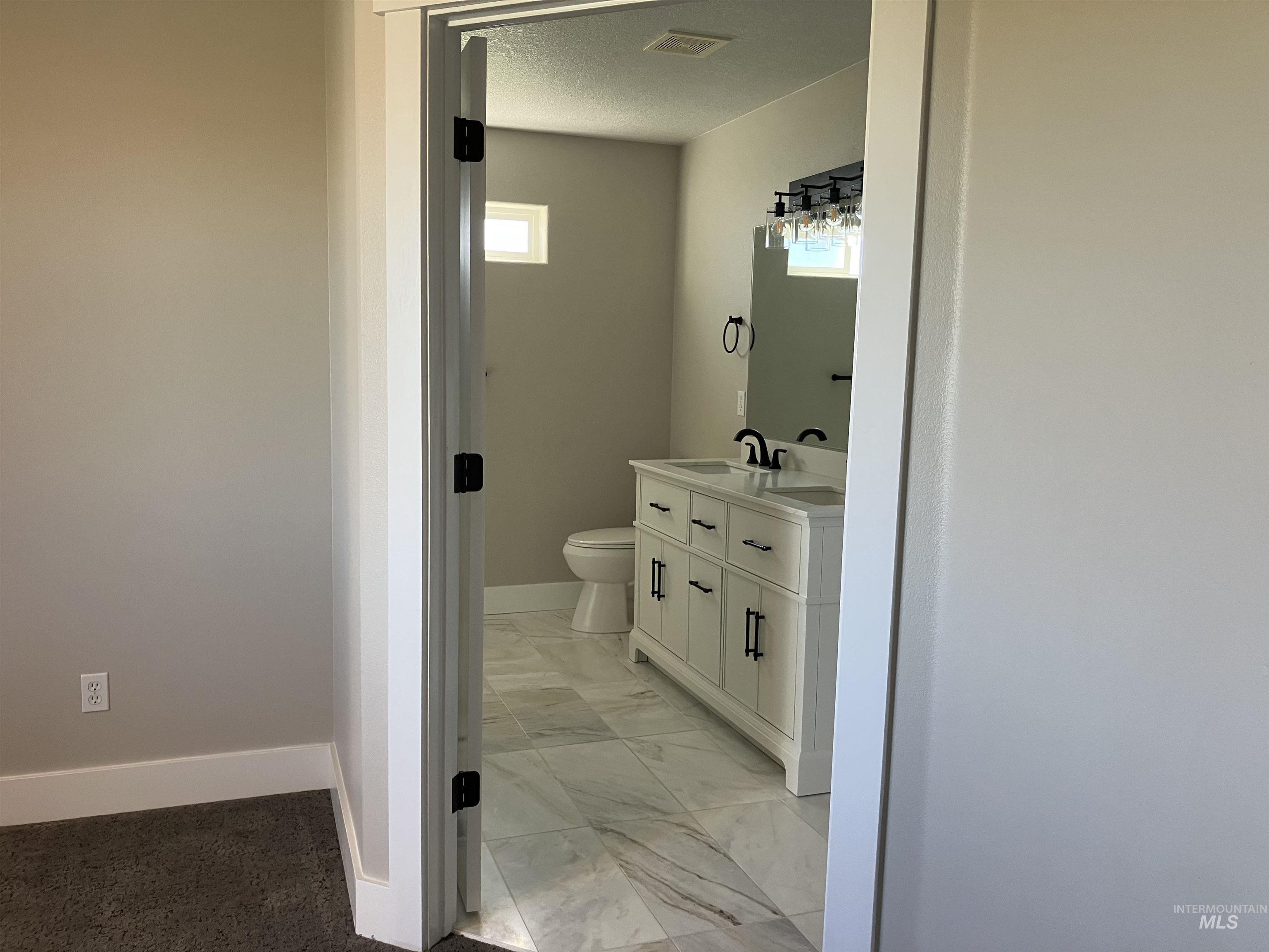 Bathroom featuring vanity, healthy amount of natural light, and light marble finish floors