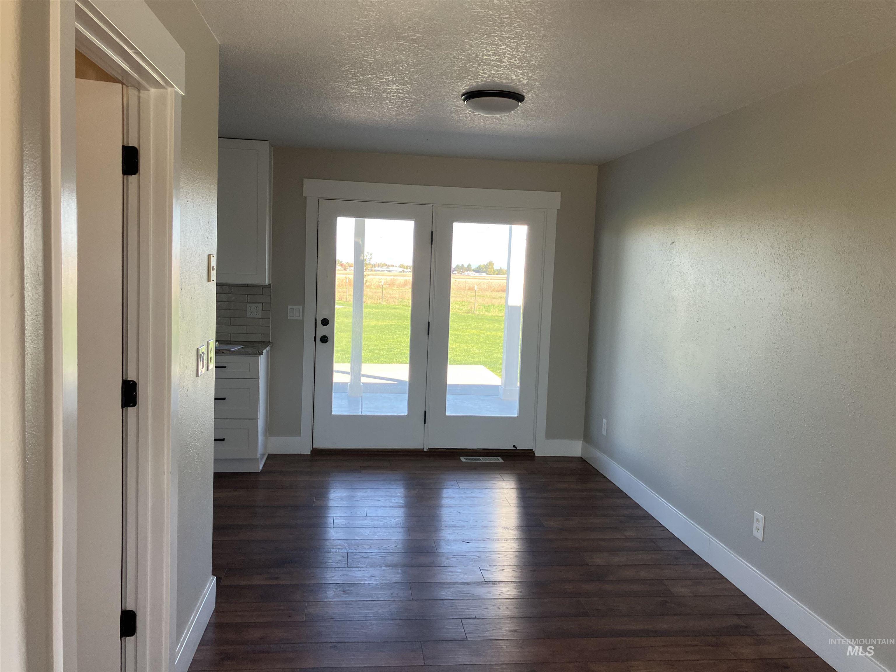 Doorway to outside featuring a textured ceiling, hardwood / wood-style flooring, and a textured wall