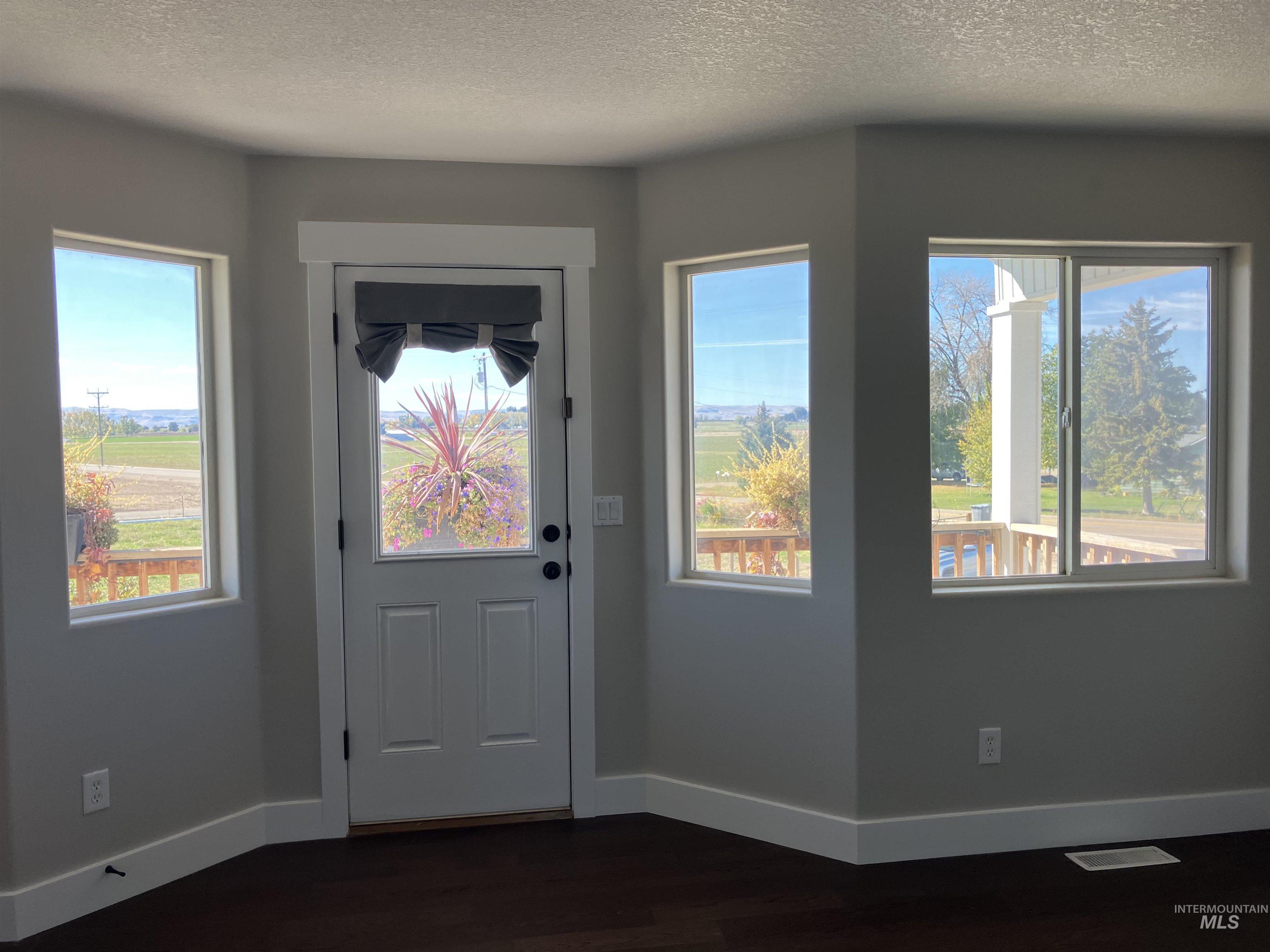 Upstairs Bedroom featuring a textured ceiling, healthy amount of natural light, and wood finished floors and access to a balcony deck