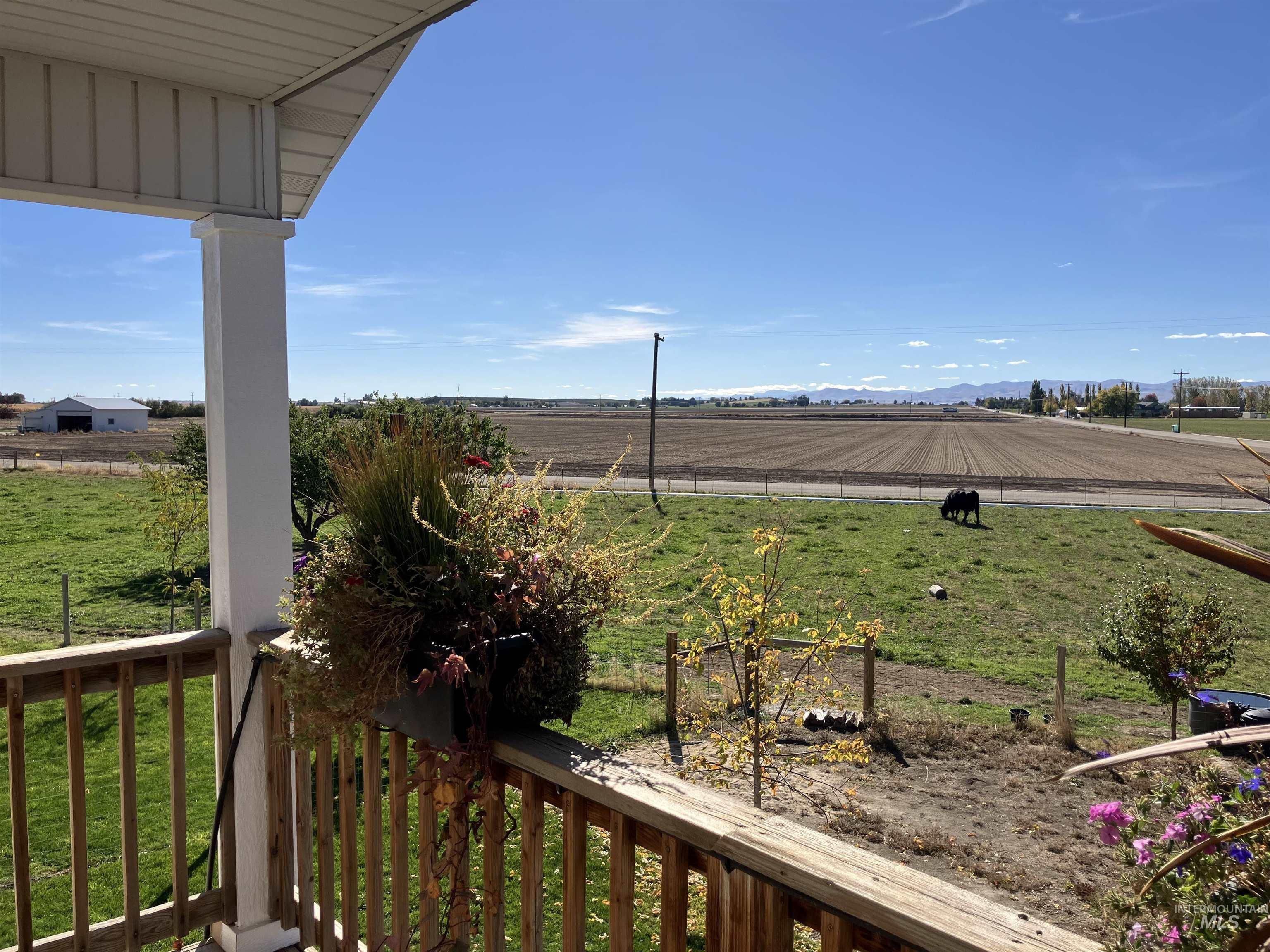 View of green lawn with a rural view, a balcony, and agricultural area from upper bedroom or could be a bonus room.