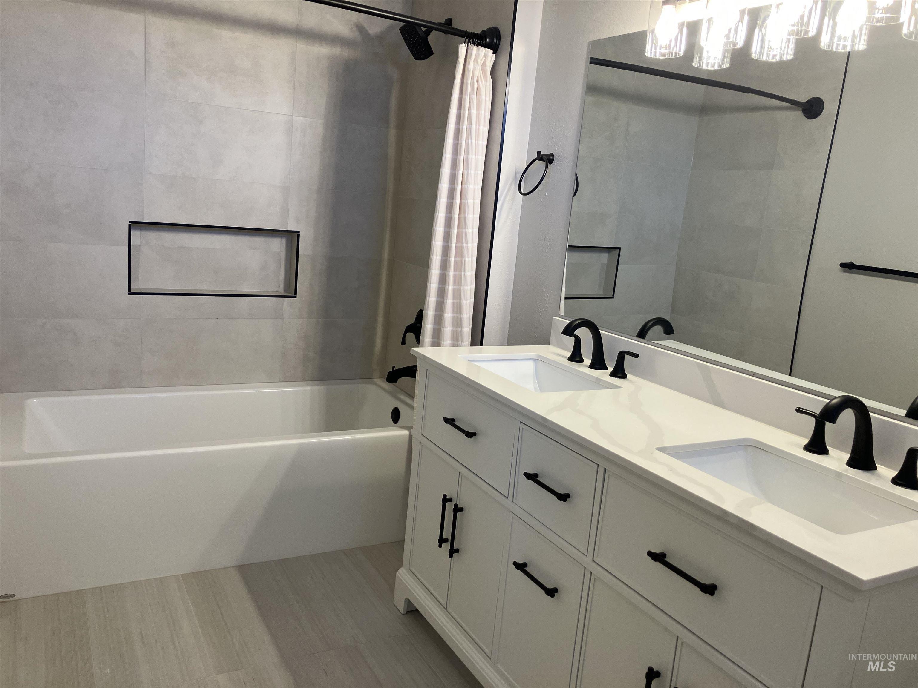 Bathroom featuring double vanity and shower / tub combo with curtain