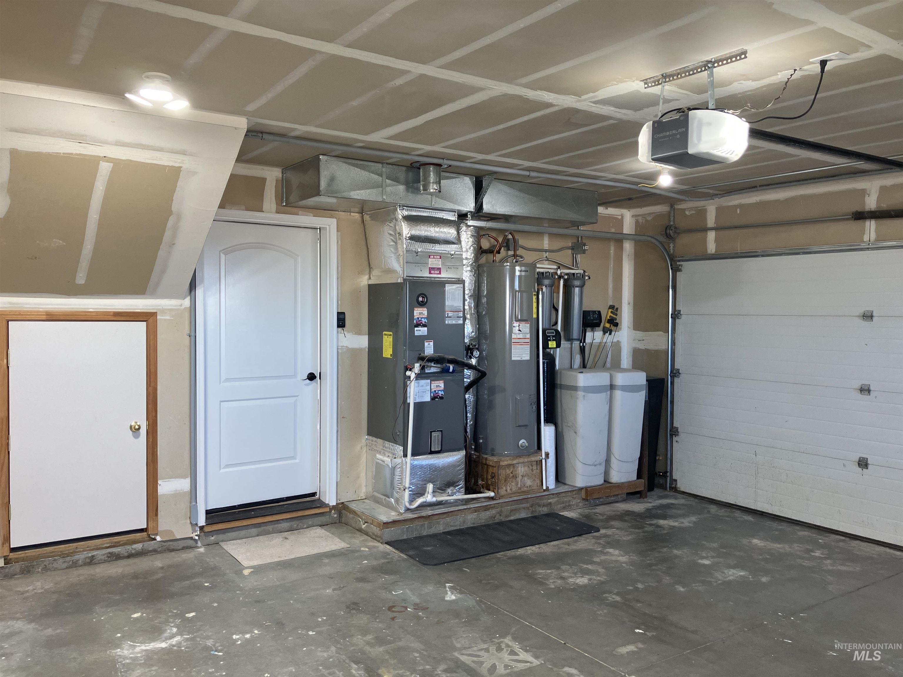 Garage featuring electric water heater, heating unit, and a garage door opener