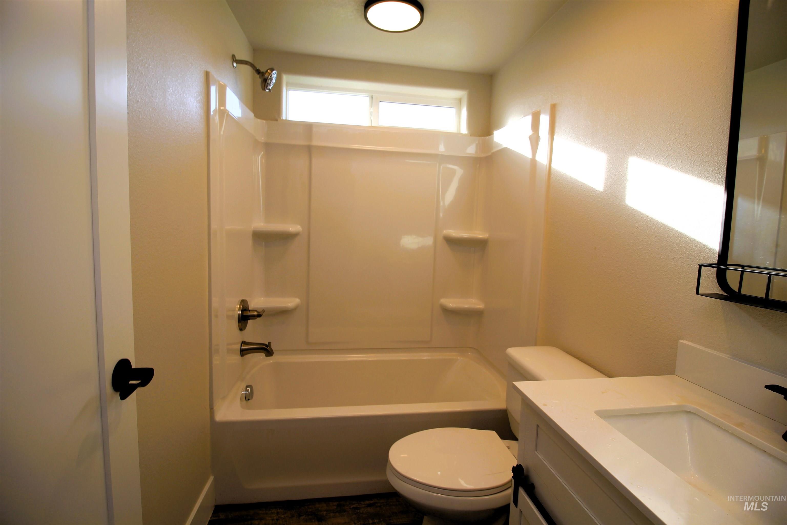Full bath featuring vanity, shower / tub combination, and a textured wall