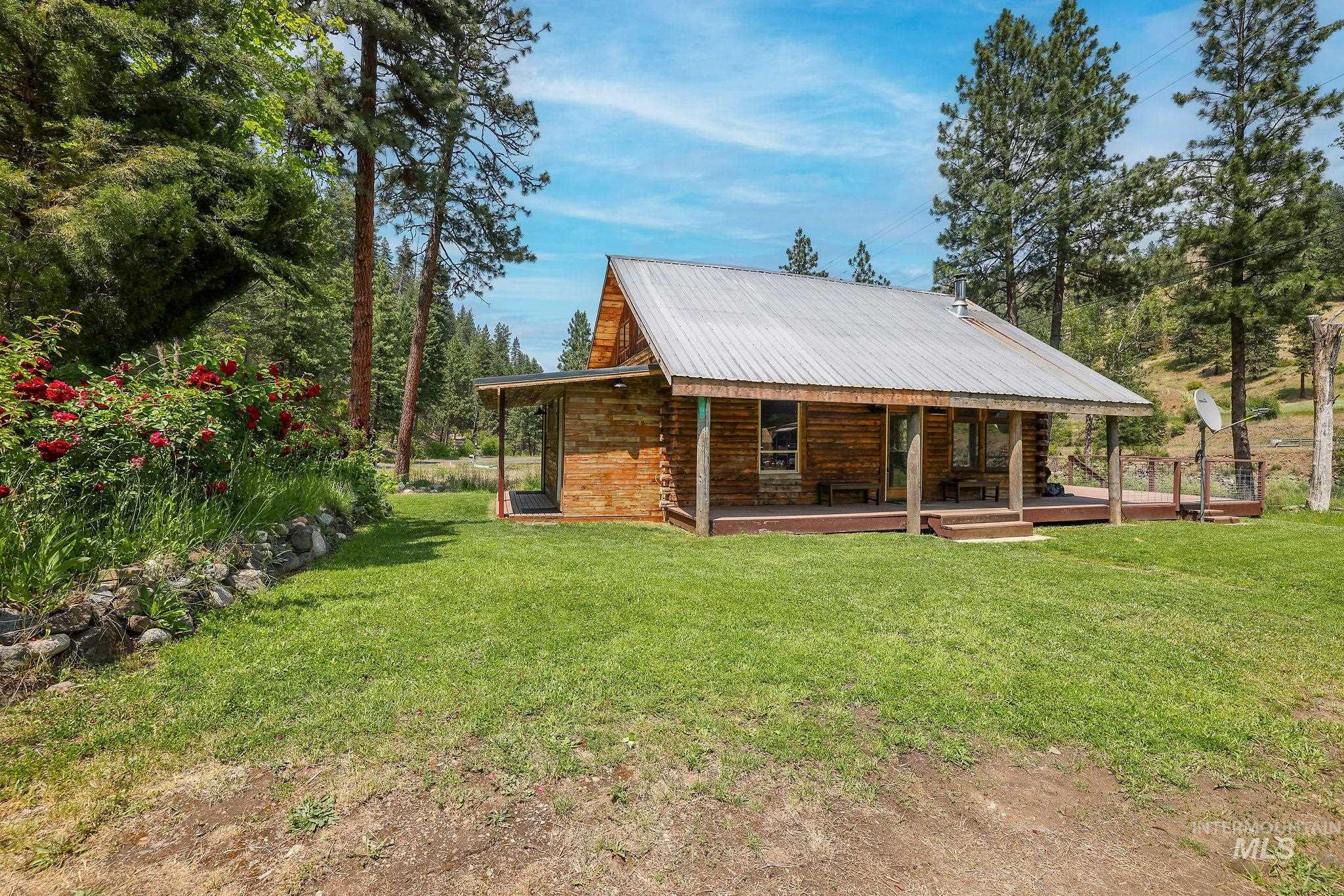 Back of property featuring covered porch, a yard, a metal roof, and log exterior
