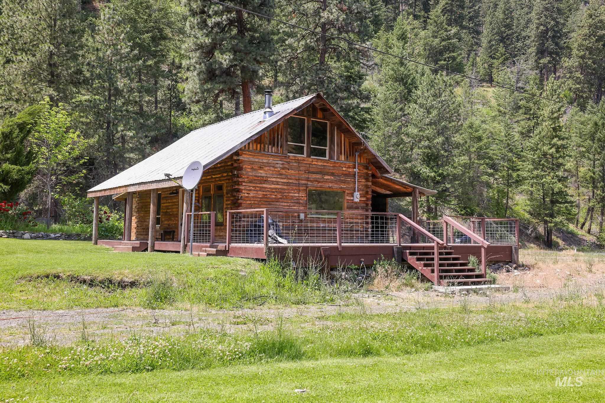 View of front of property with a wooded view, log exterior, and a front lawn