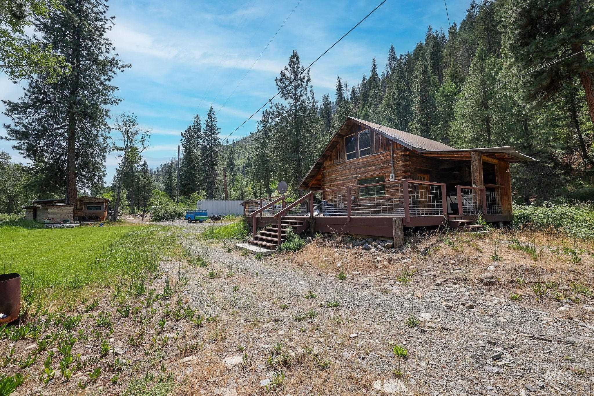 View of home's exterior with a forest view, a deck, driveway, and log siding