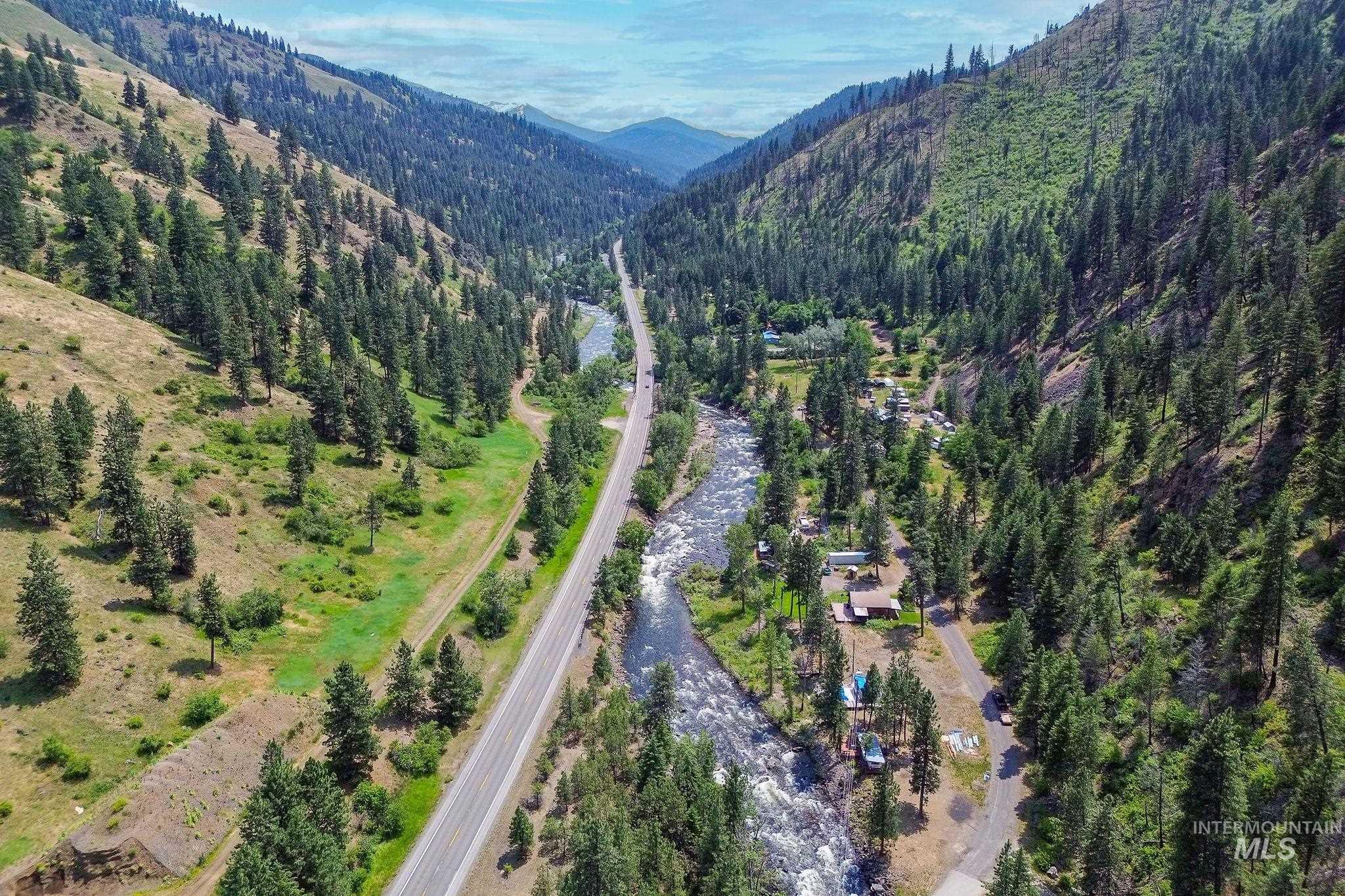 Aerial view of property and surrounding area featuring mountains and a heavily wooded area