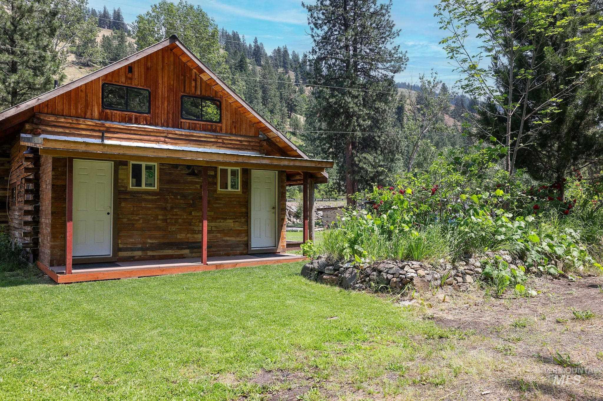 Back of house with a yard, log exterior, and a wooded view