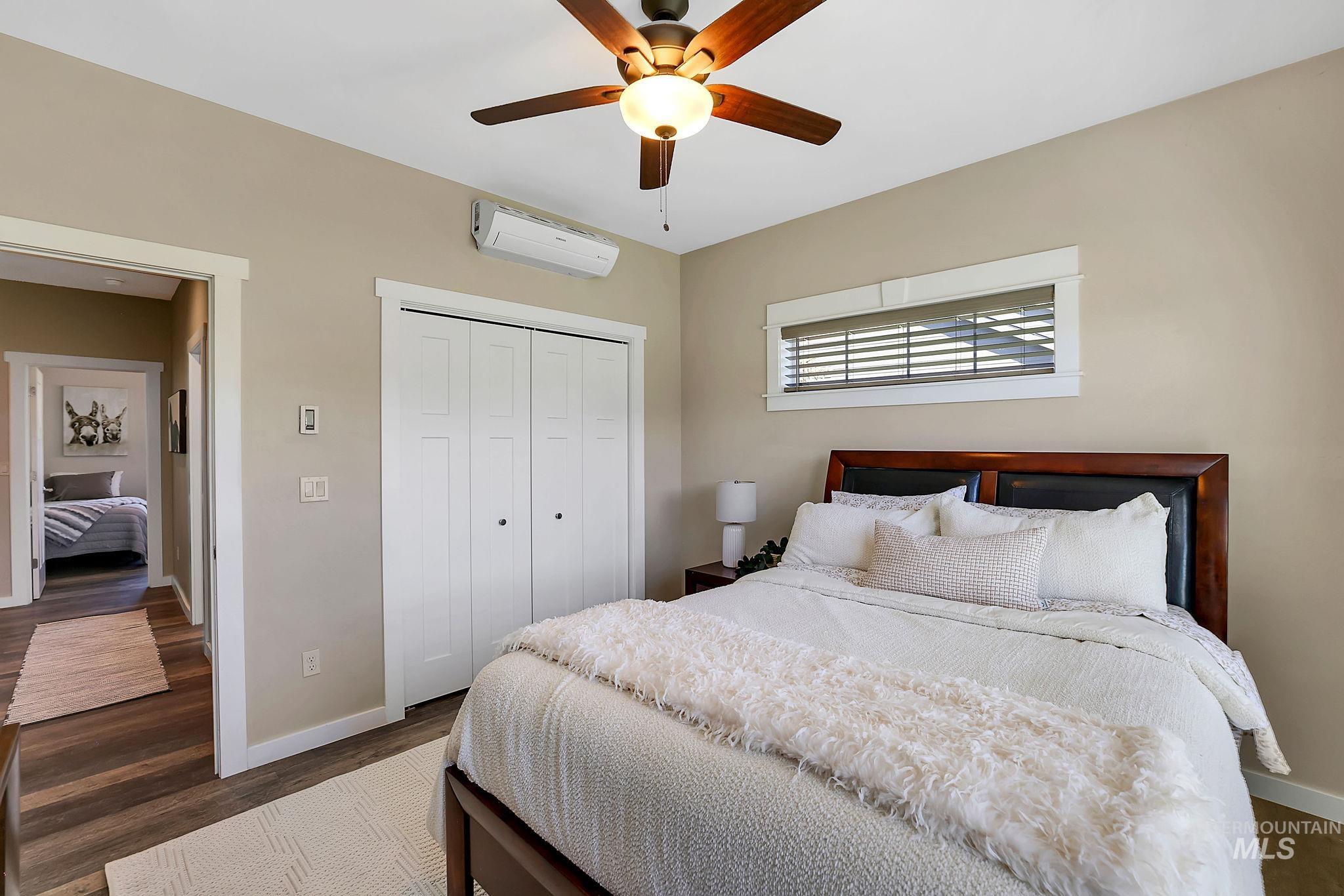 Bedroom featuring dark wood-style flooring, a closet, a ceiling fan, and an AC wall unit