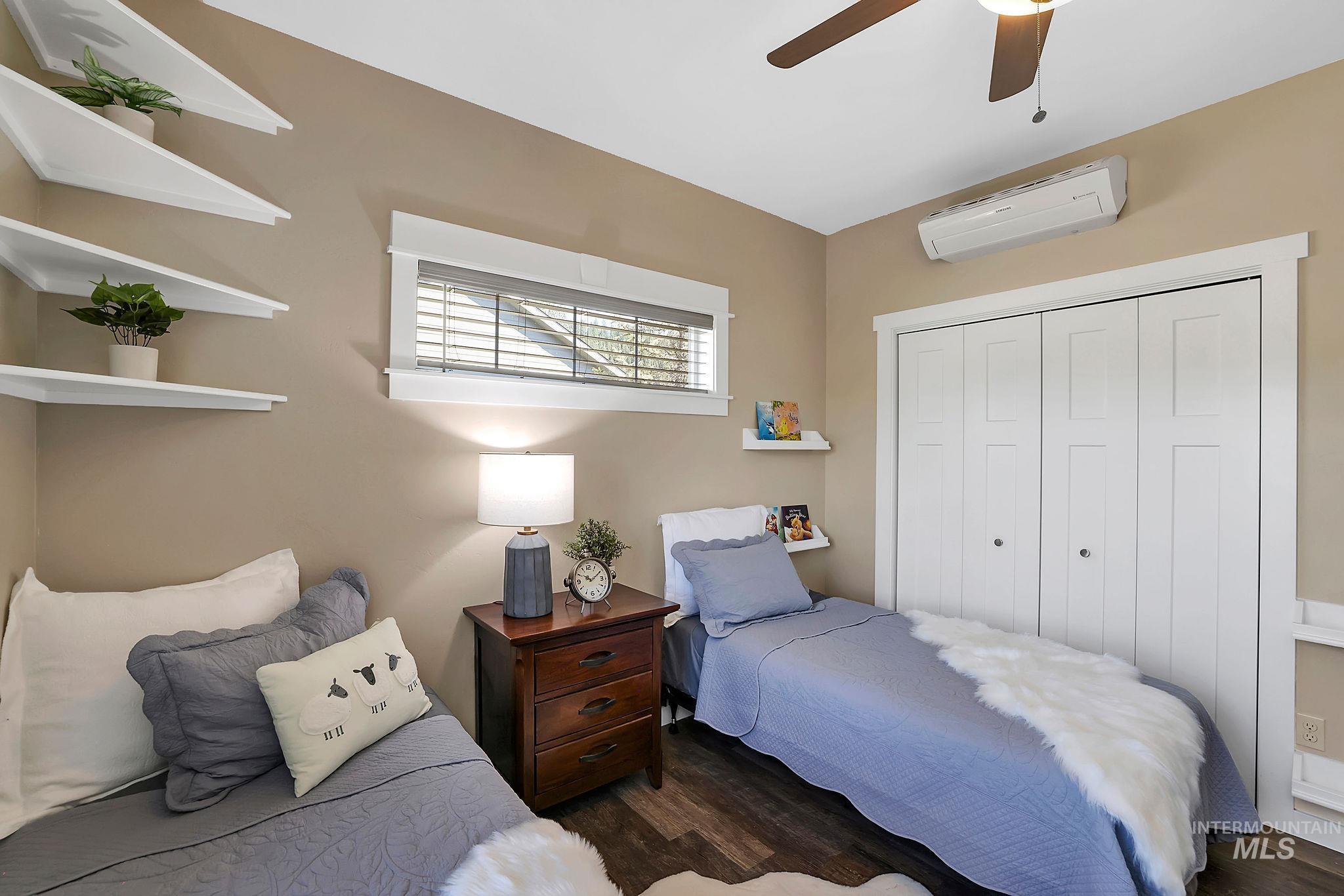 Bedroom featuring wood finished floors, a closet, a wall unit AC, and ceiling fan