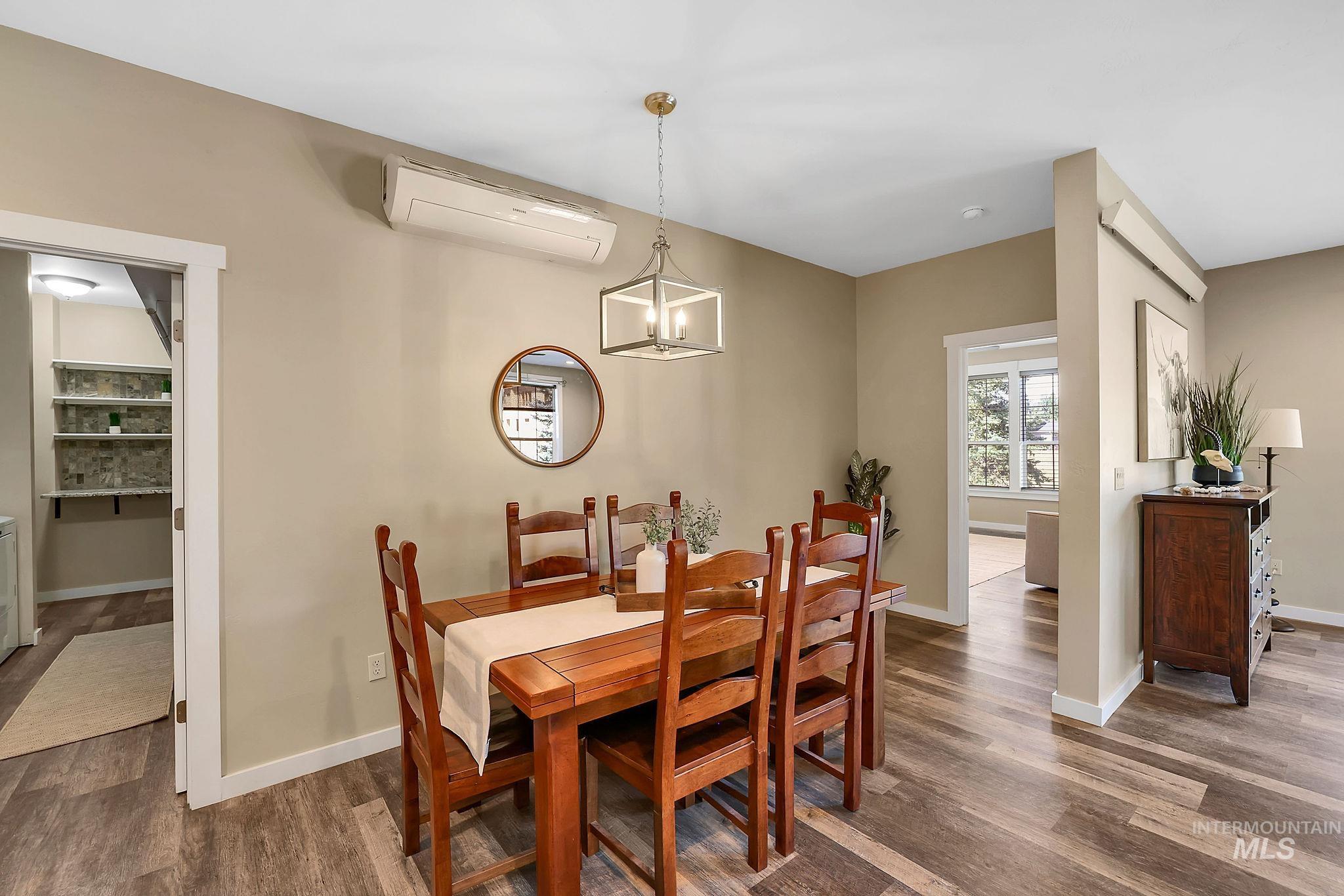 Dining space featuring wood finished floors, a wall mounted air conditioner, and a chandelier