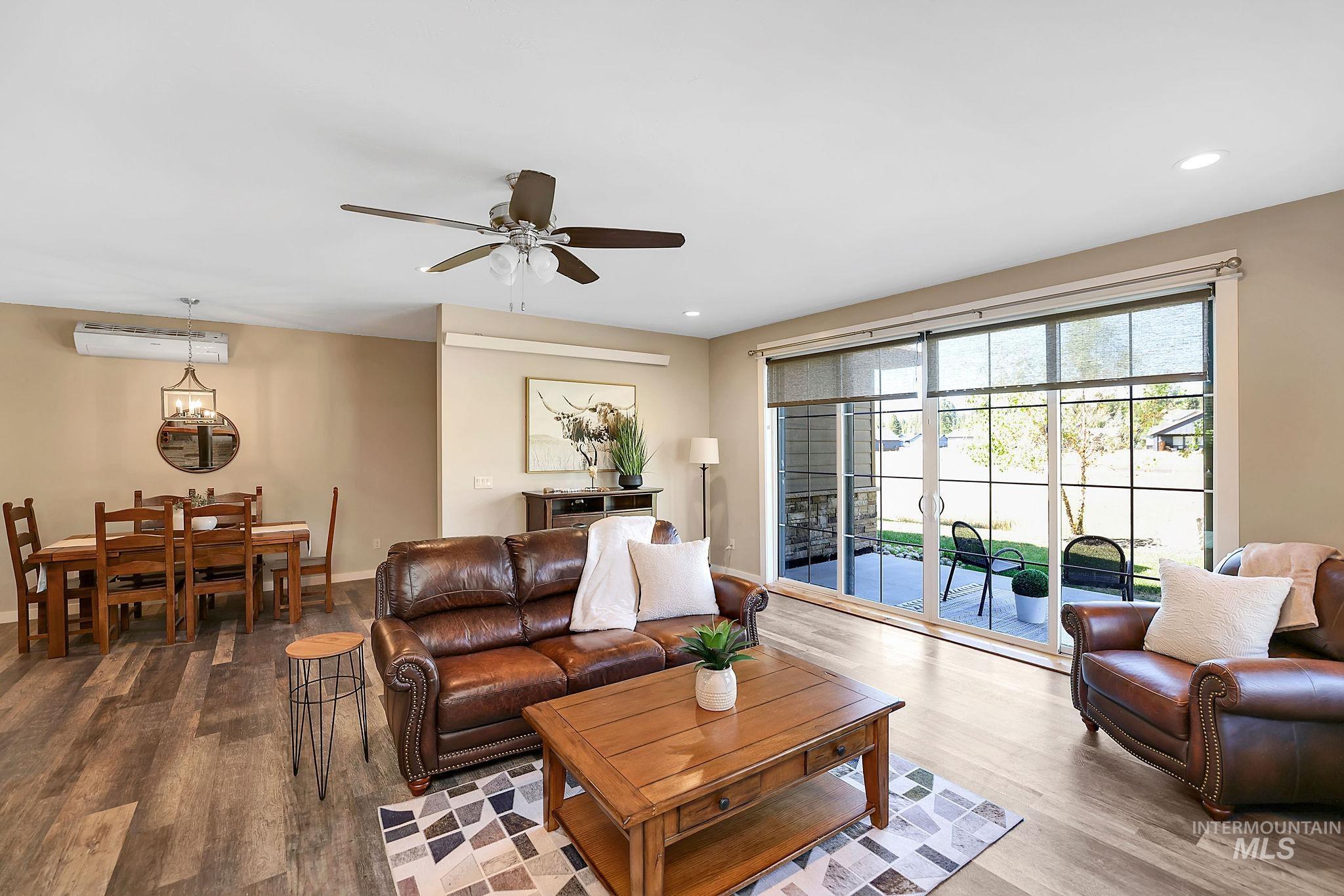 Living area with wood finished floors, ceiling fan, recessed lighting, and an AC wall unit