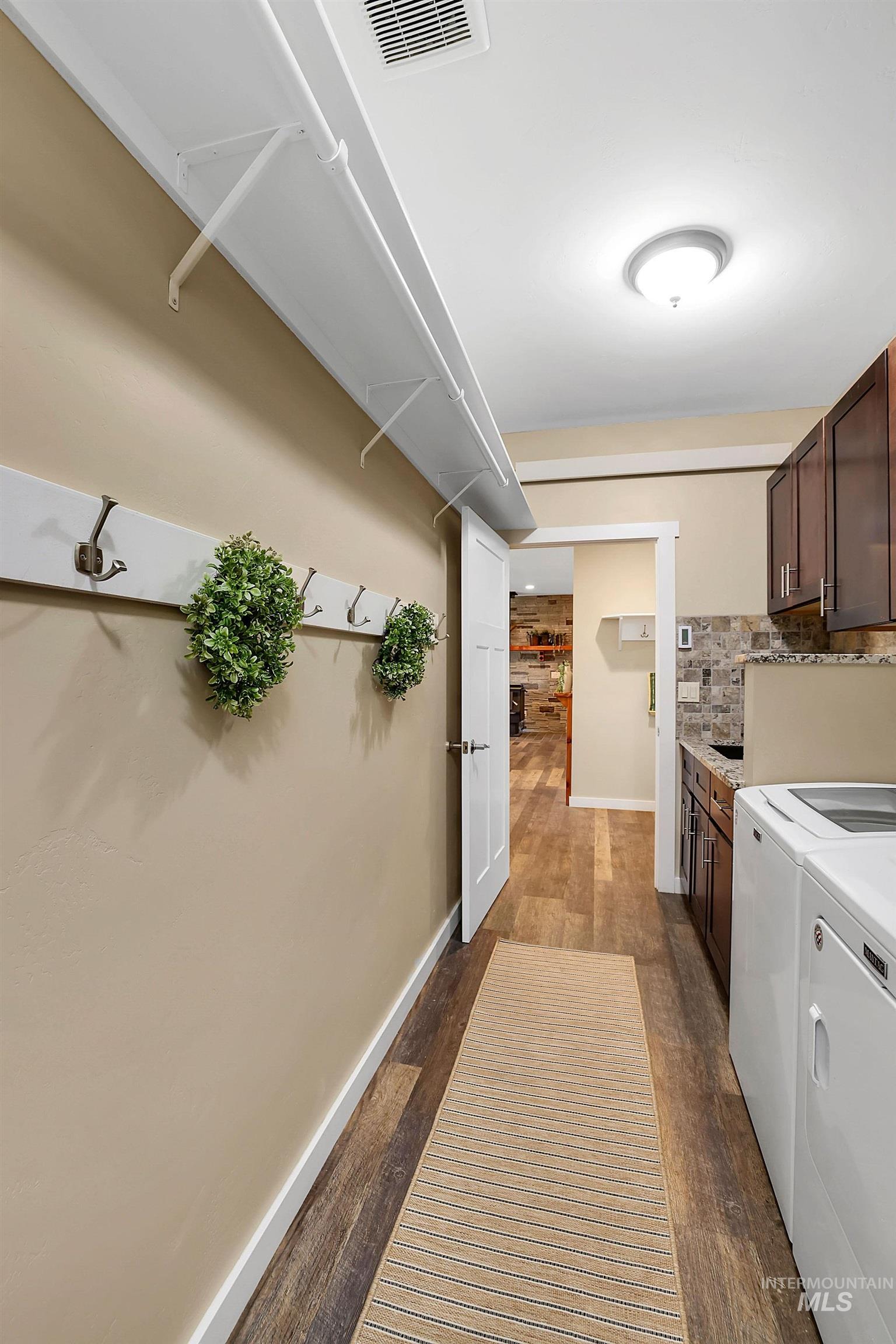 Laundry room featuring independent washer and dryer, dark wood-style flooring, and cabinet space