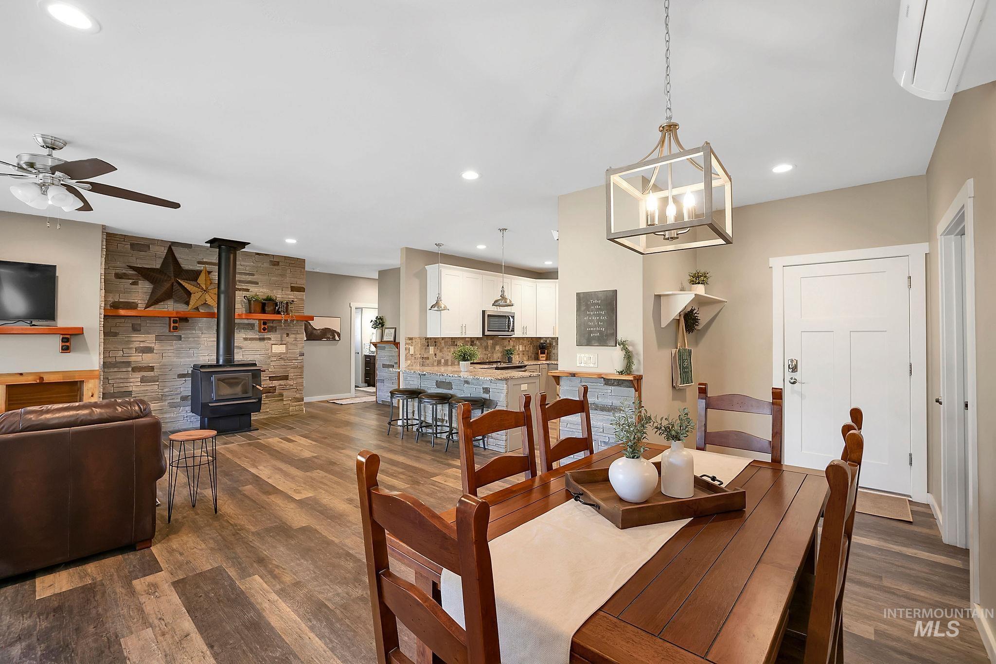 Dining space featuring a wood stove, dark wood-style floors, a wall mounted AC, recessed lighting, and a ceiling fan