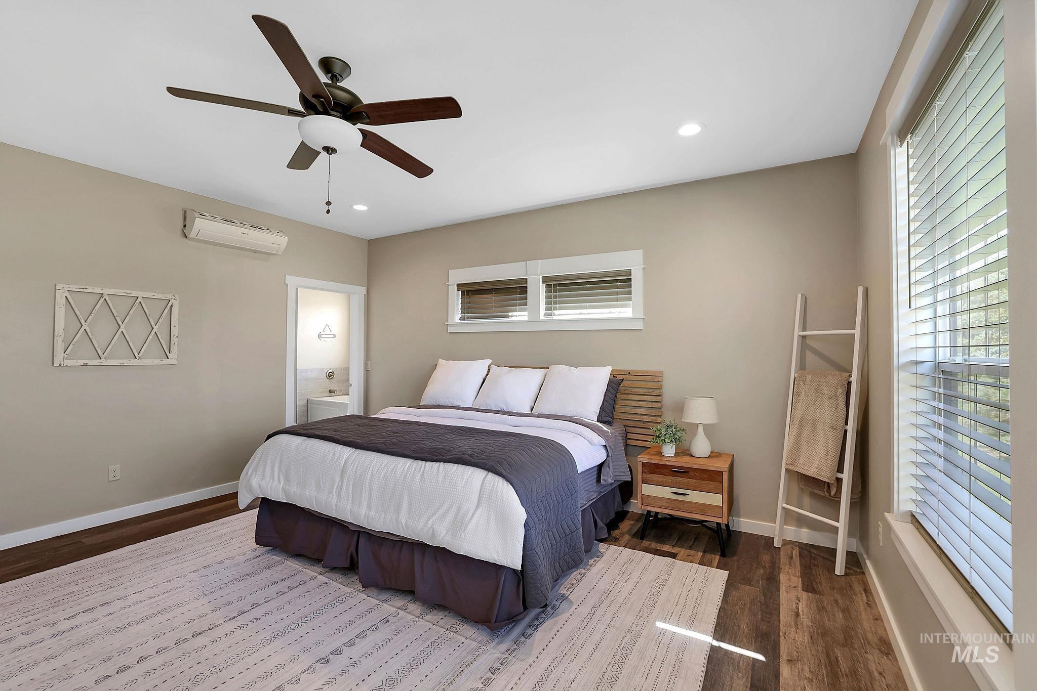 Bedroom with a ceiling fan, dark wood-type flooring, recessed lighting, connected bathroom, and an AC wall unit