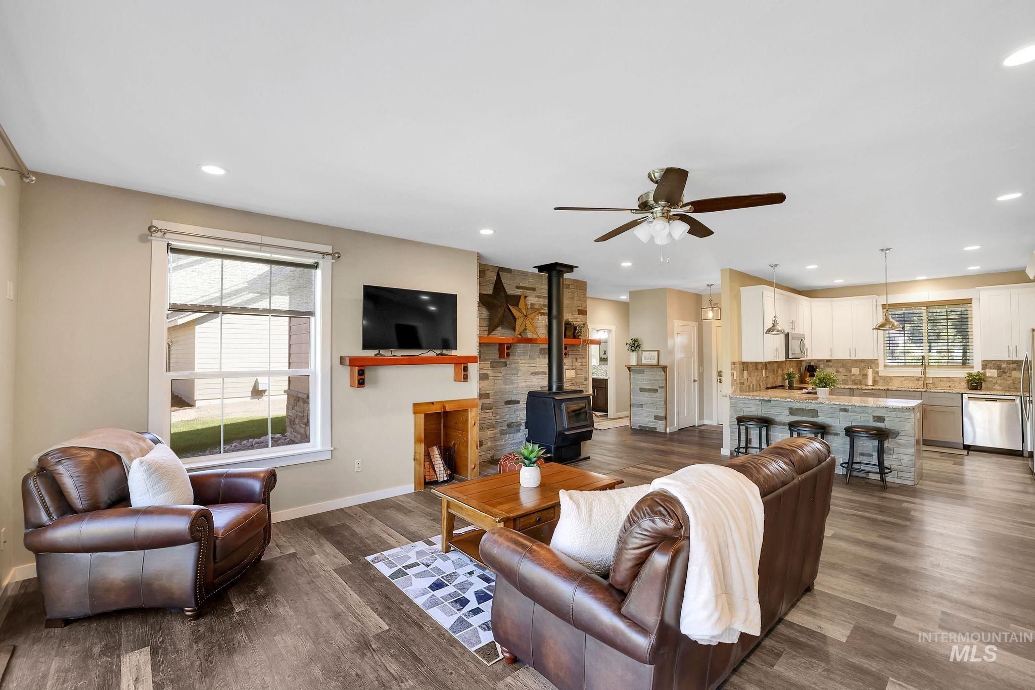 Living area featuring a wood stove, dark wood-type flooring, ceiling fan, and recessed lighting