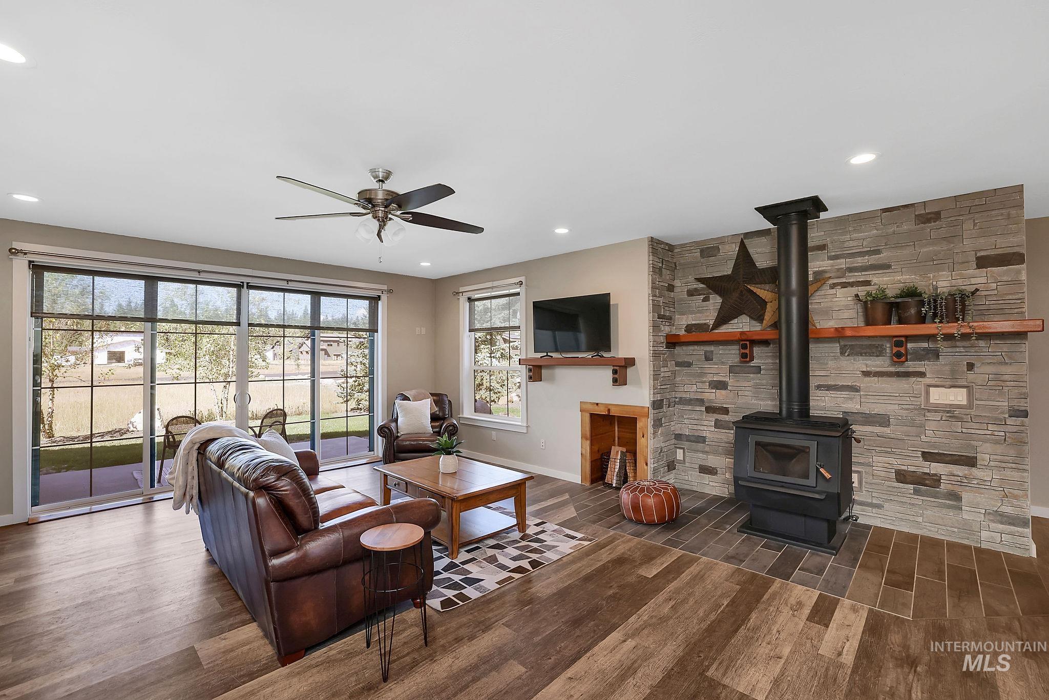 Living area featuring a wood stove, dark wood-style flooring, recessed lighting, and a ceiling fan