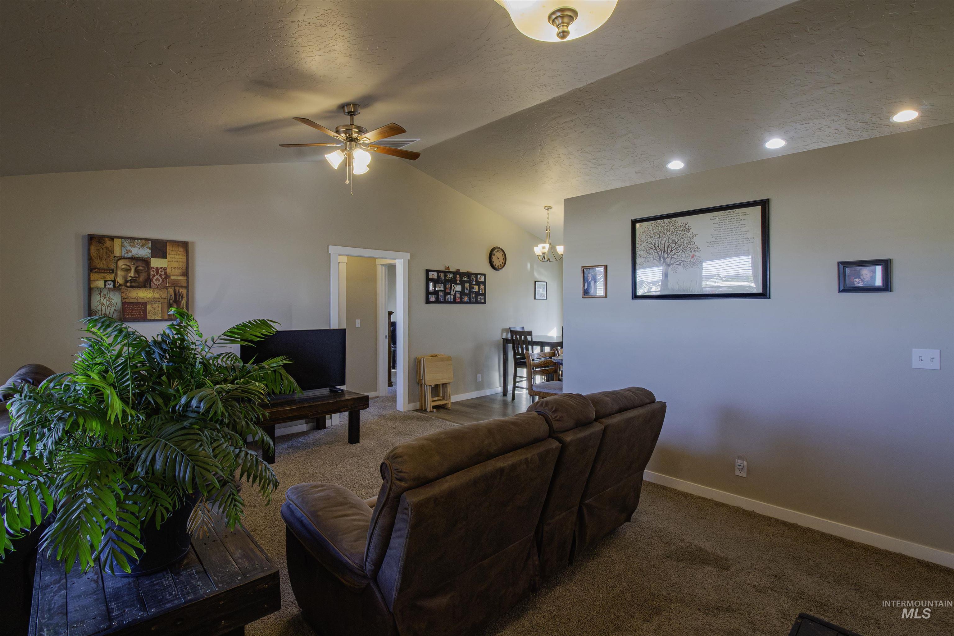 Carpeted living area with a textured ceiling, and a ceiling fan.