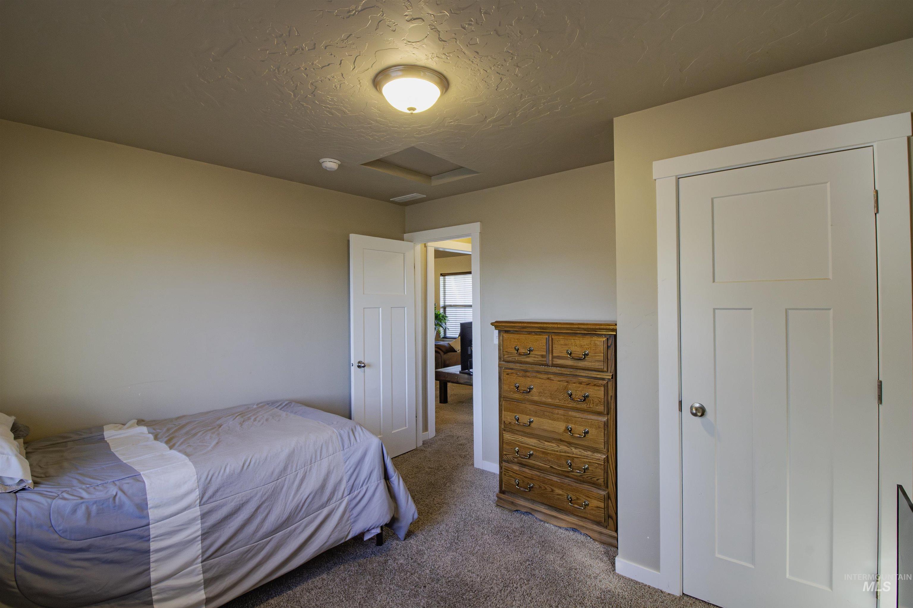 Carpeted bedroom with attic access and a textured ceiling