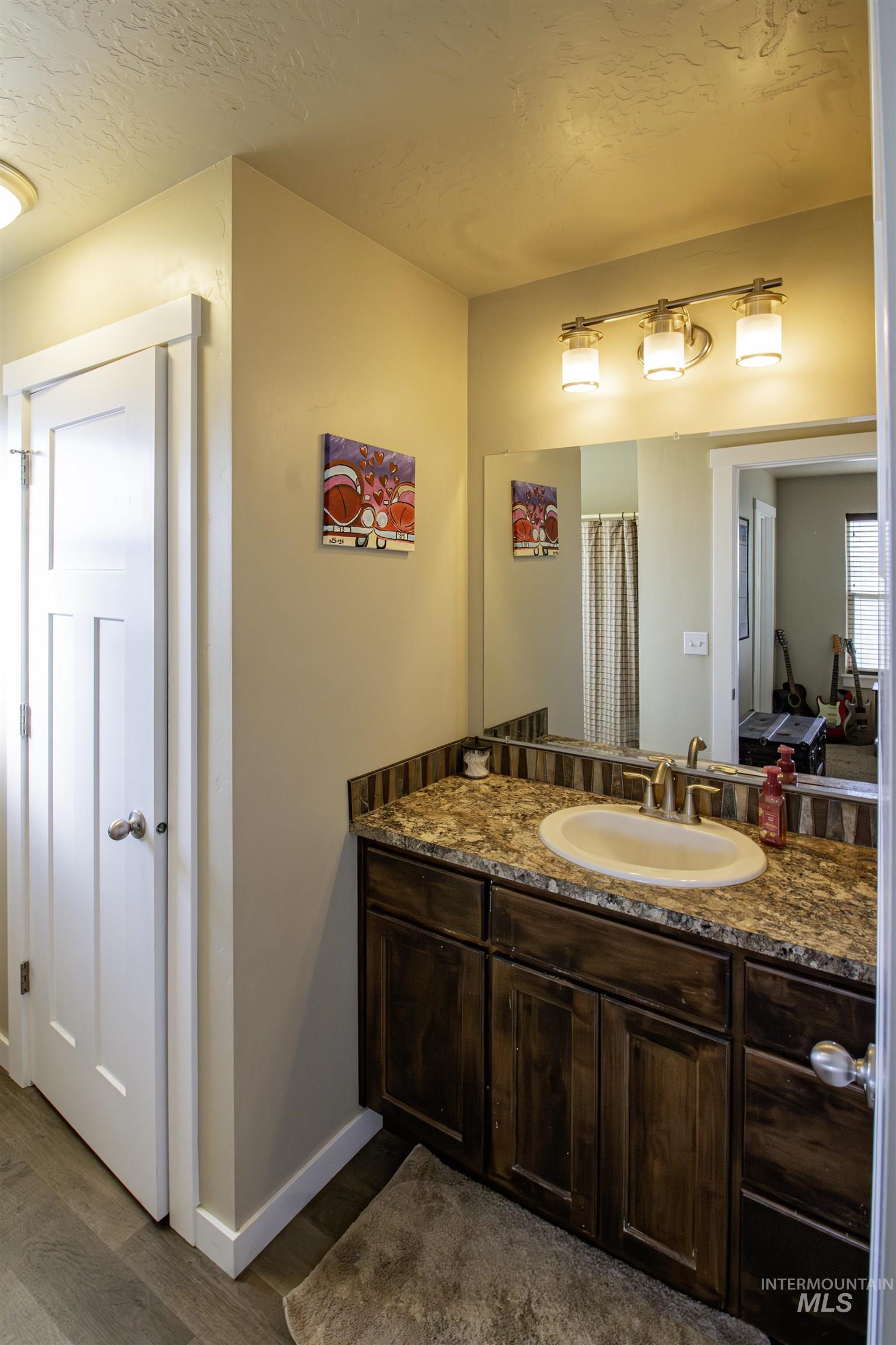 Full bath featuring vanity, dark wood-type flooring, a textured ceiling, with a walk-in shower