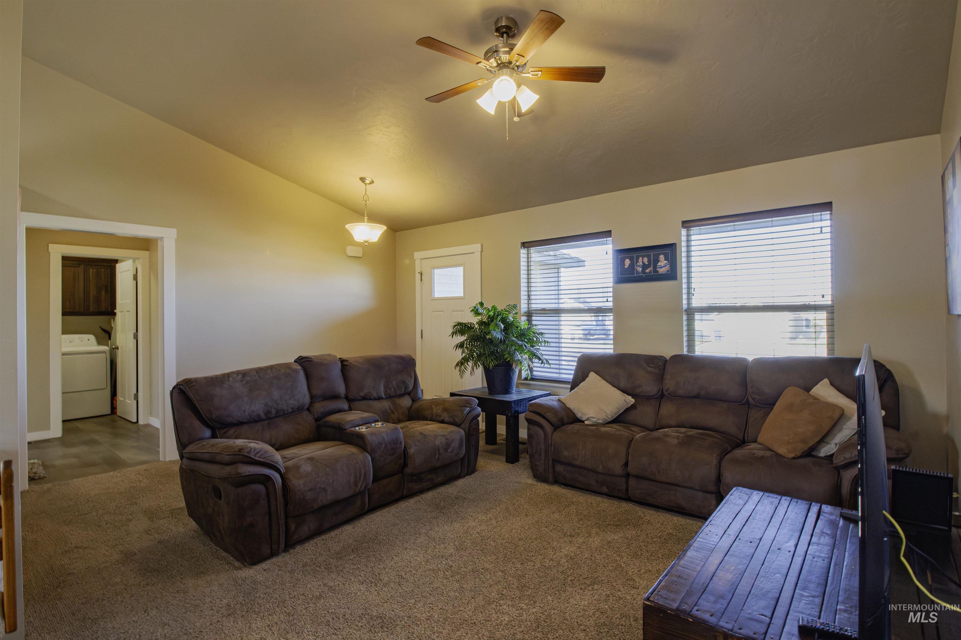 Living area featuring vaulted ceiling, carpet, and ceiling fan
