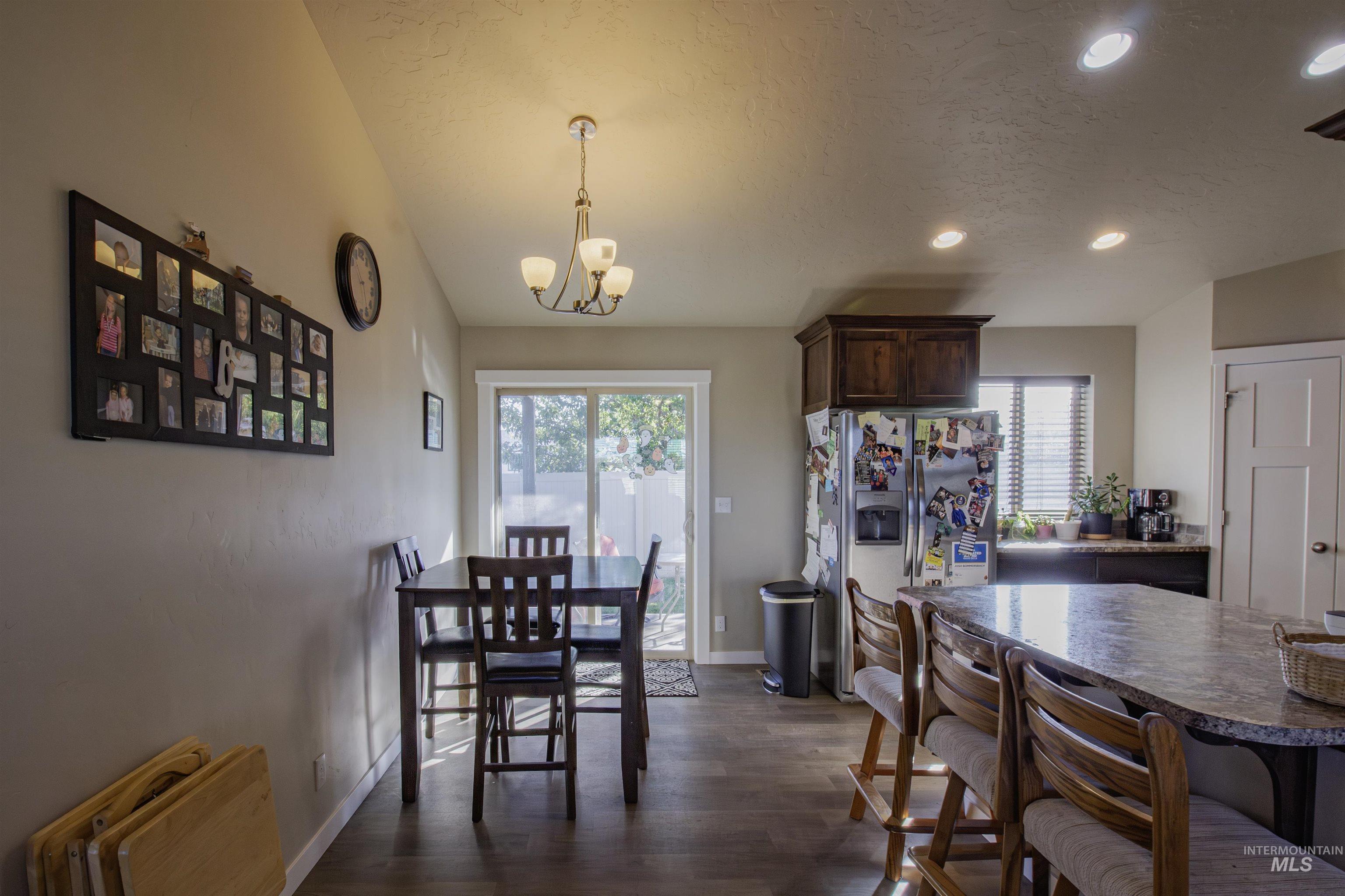 Dining area with dark wood-type flooring, plenty of natural light, recessed lighting, a textured ceiling, and a chandelier