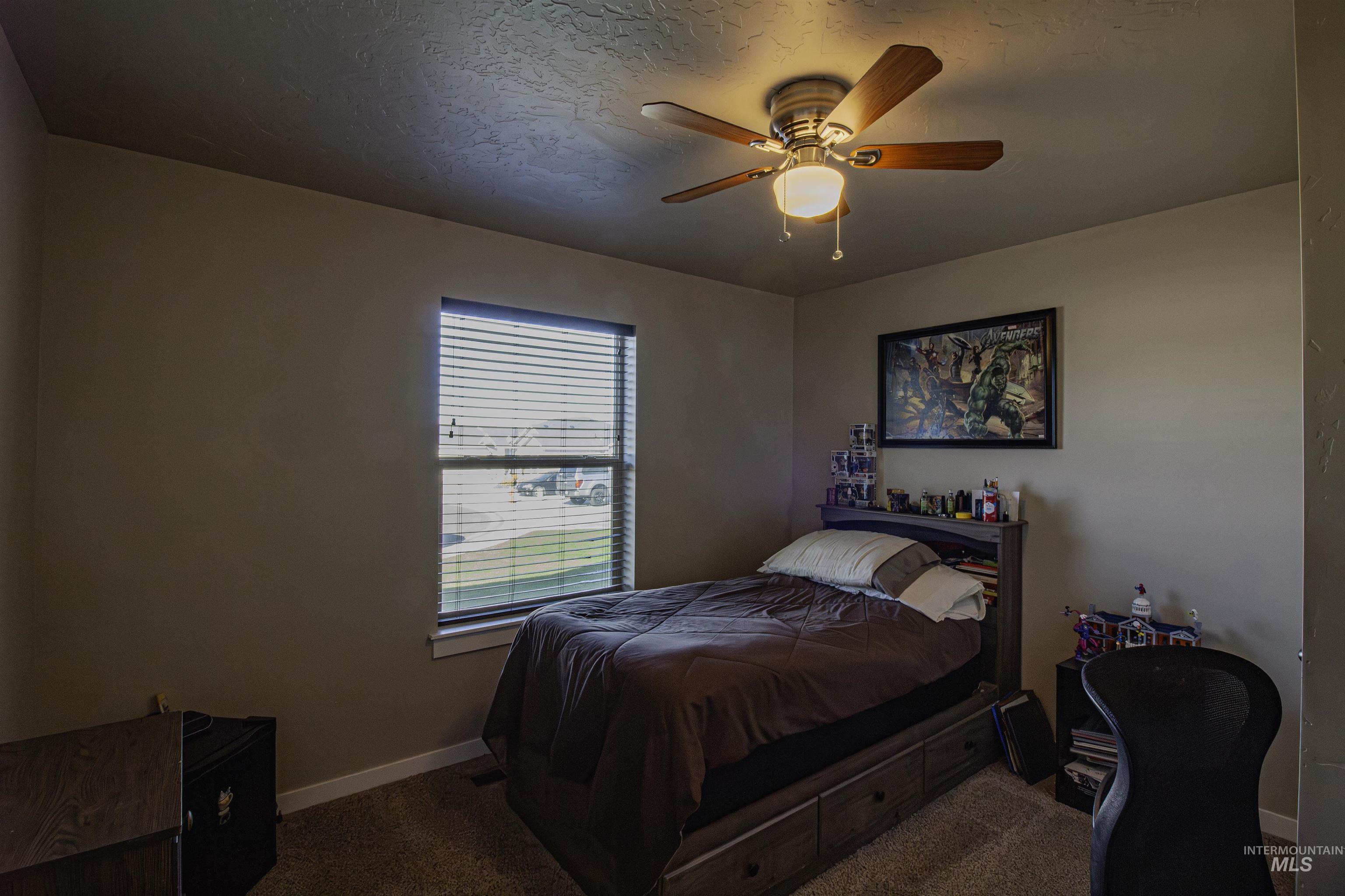 Bedroom with carpet, a textured ceiling, and a ceiling fan