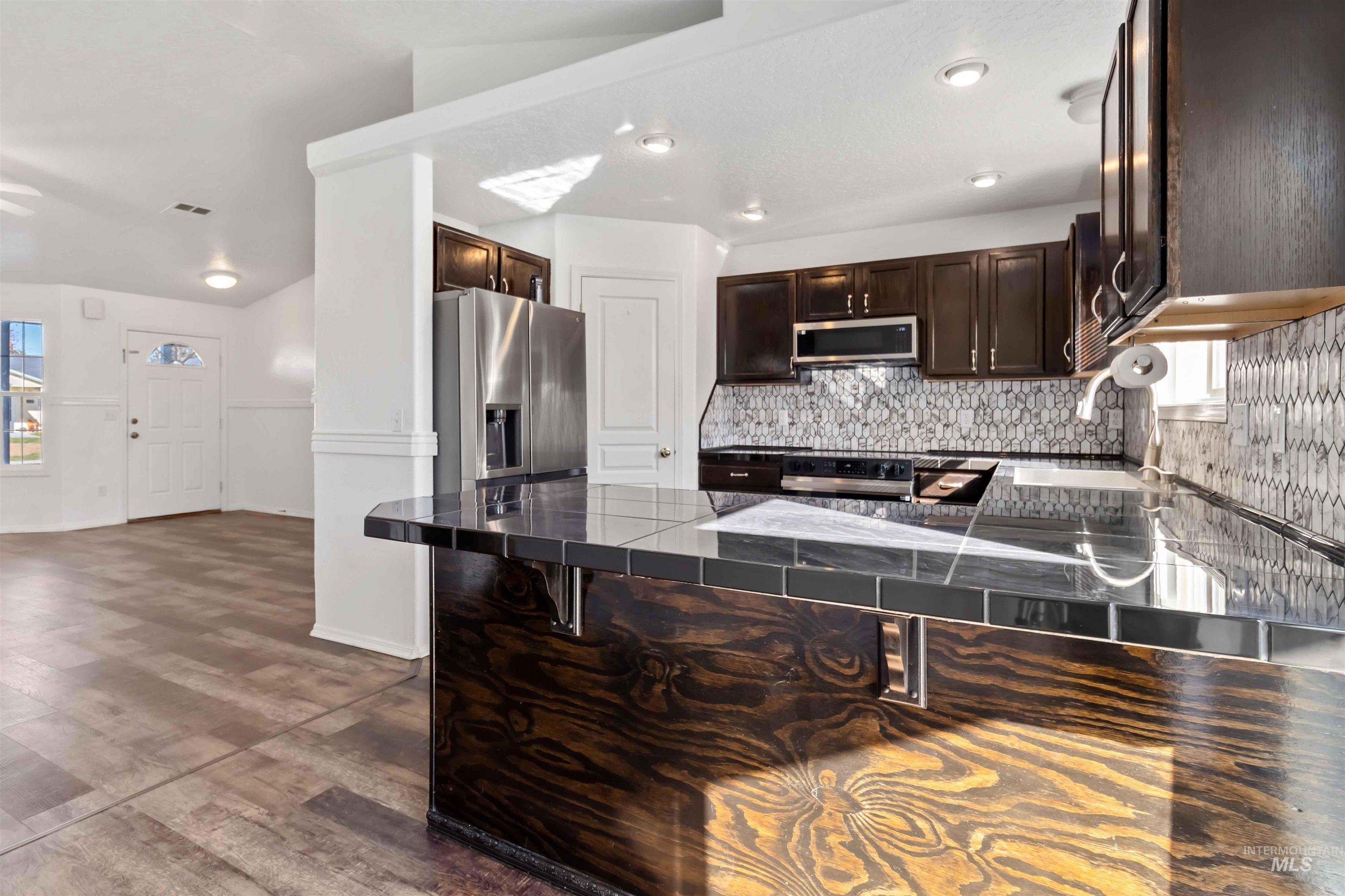 Kitchen with plenty of natural light, dark brown cabinetry, tasteful backsplash, dark countertops, and recessed lighting