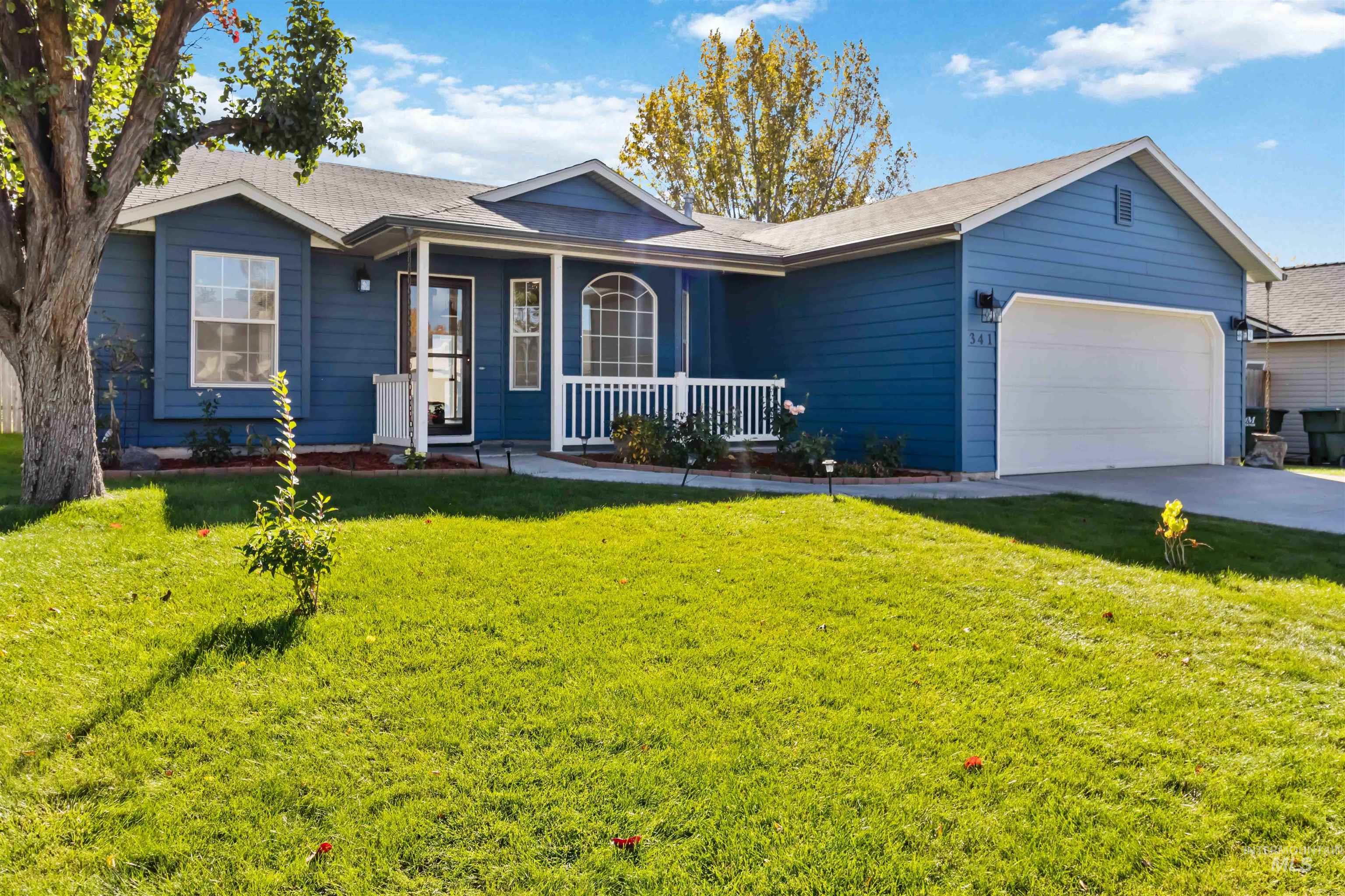 Ranch-style home featuring a porch, a front lawn, an attached garage, and concrete driveway