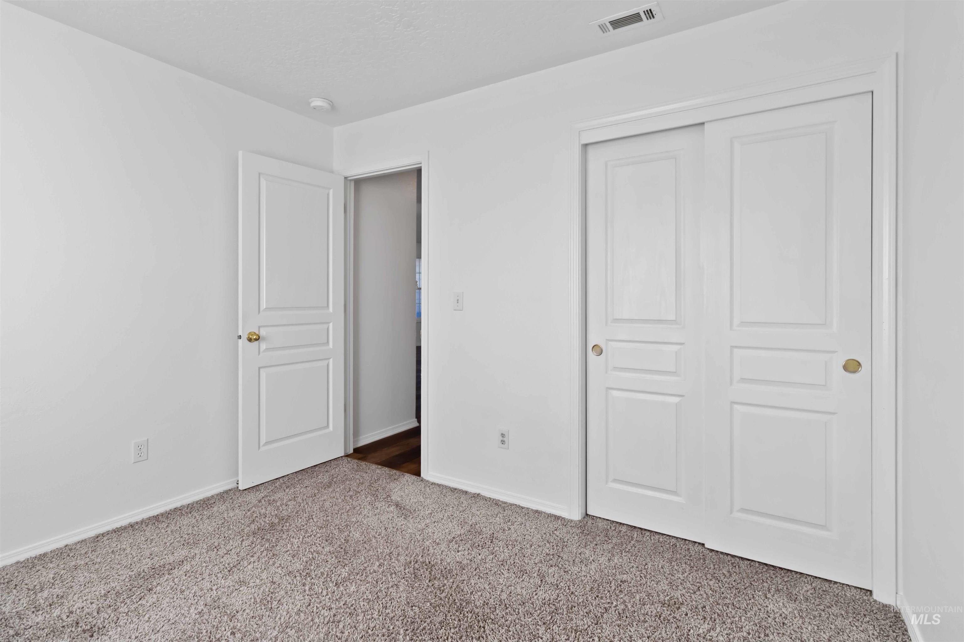 Unfurnished bedroom with dark carpet, a closet, and a textured ceiling
