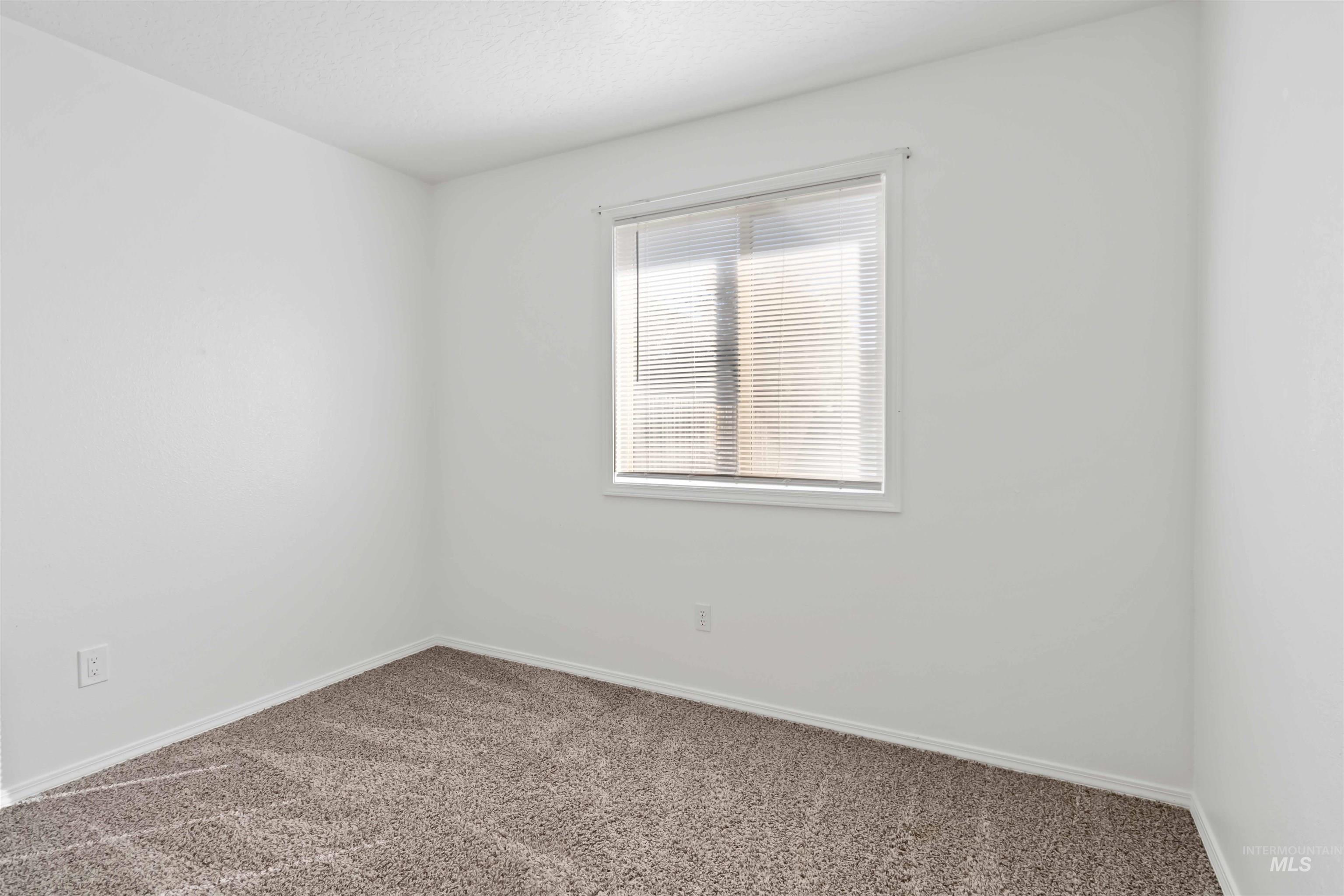 Carpeted empty room featuring baseboards and a textured ceiling