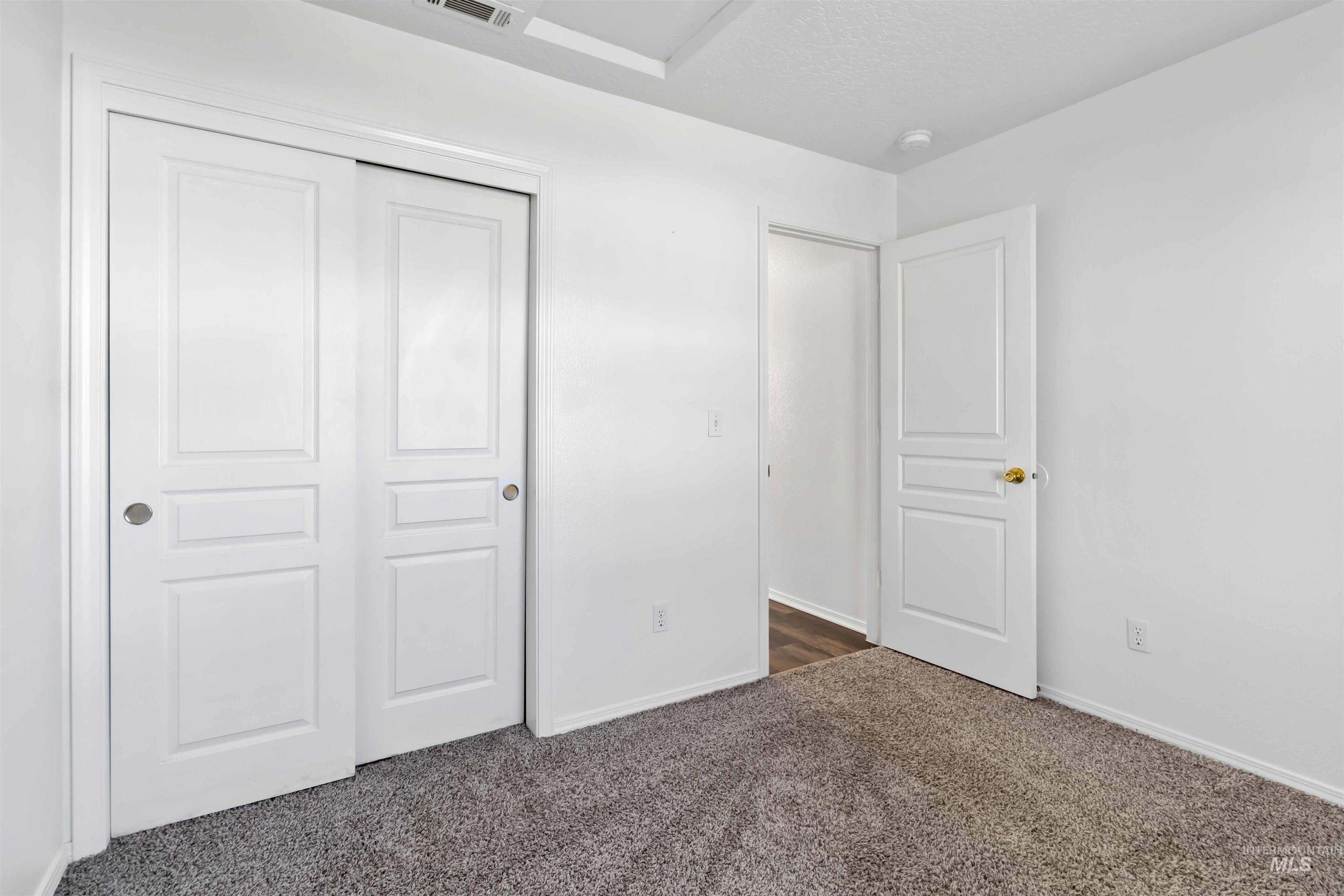 Unfurnished bedroom with dark colored carpet, a closet, and a textured ceiling