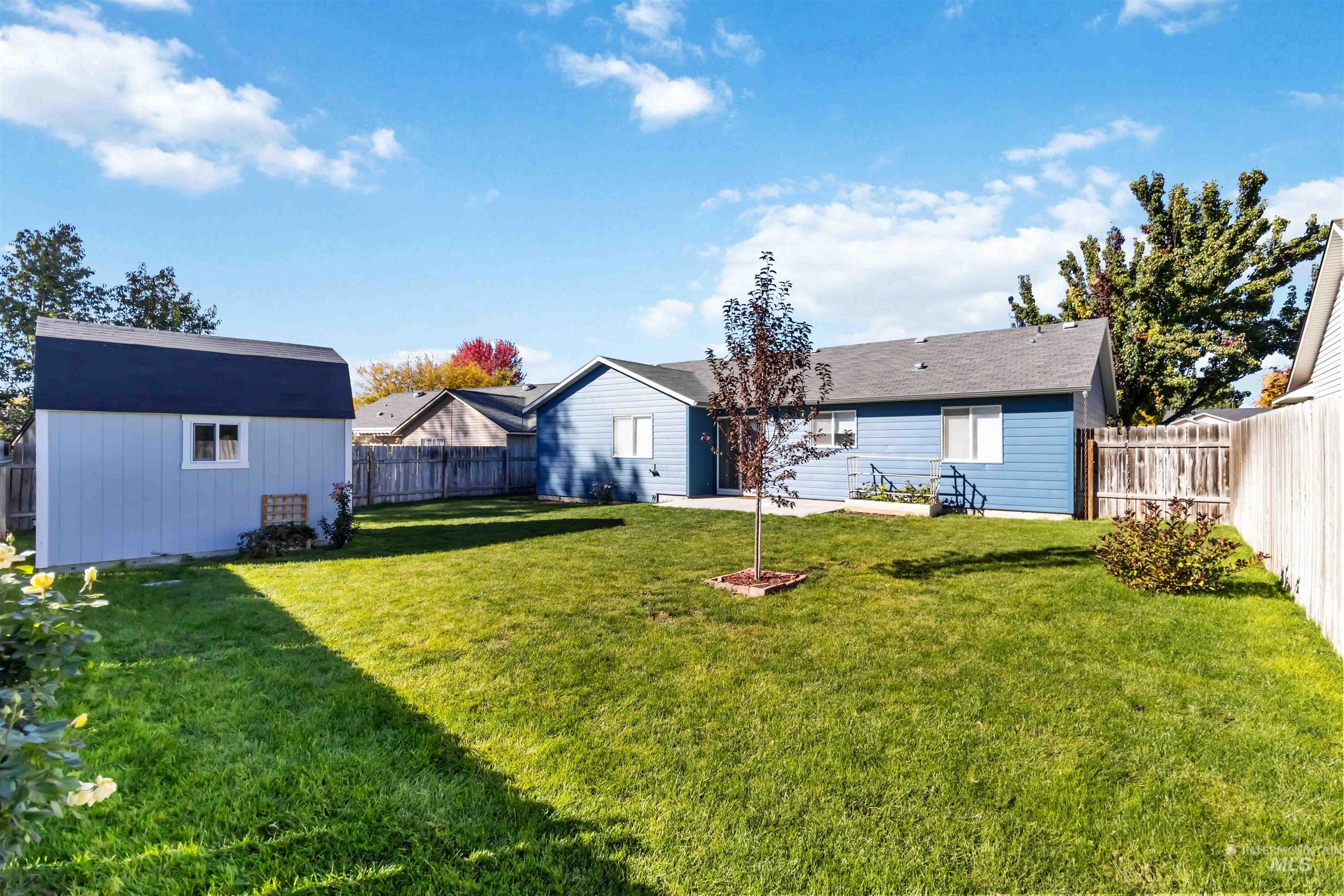 Fenced backyard with a storage unit and a patio area