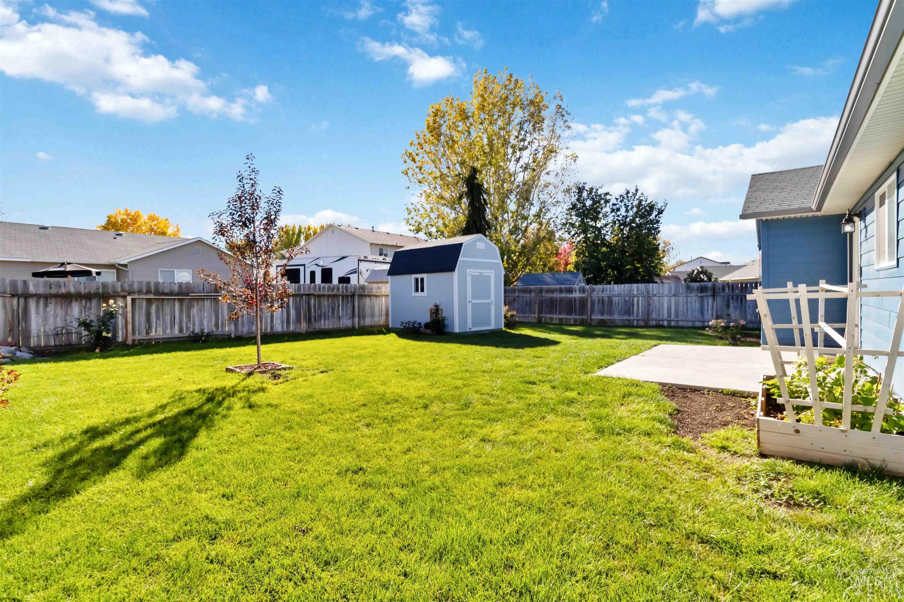 Fenced backyard featuring a storage shed and a residential view