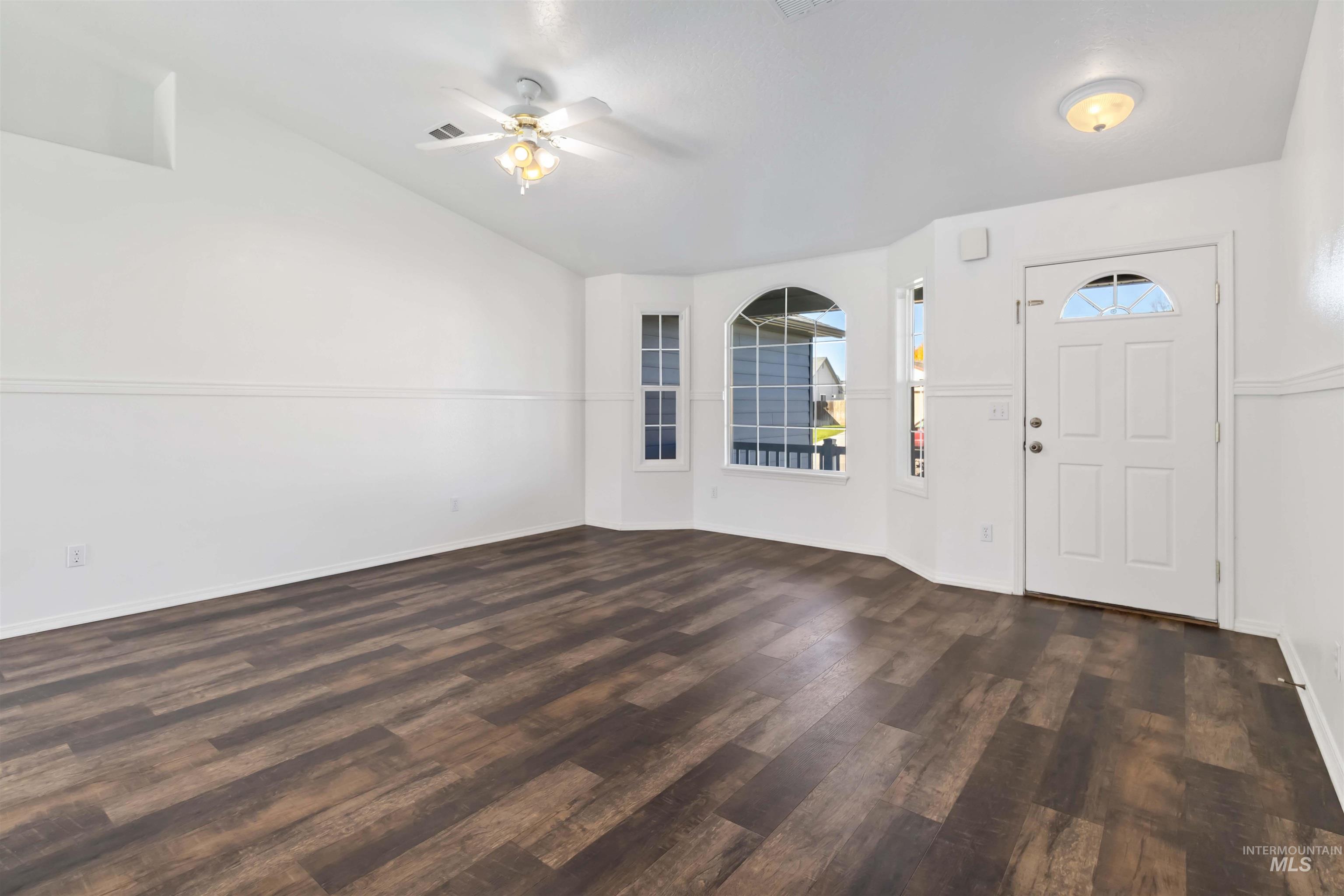 Foyer with dark wood-type flooring, ceiling fan, and vaulted ceiling