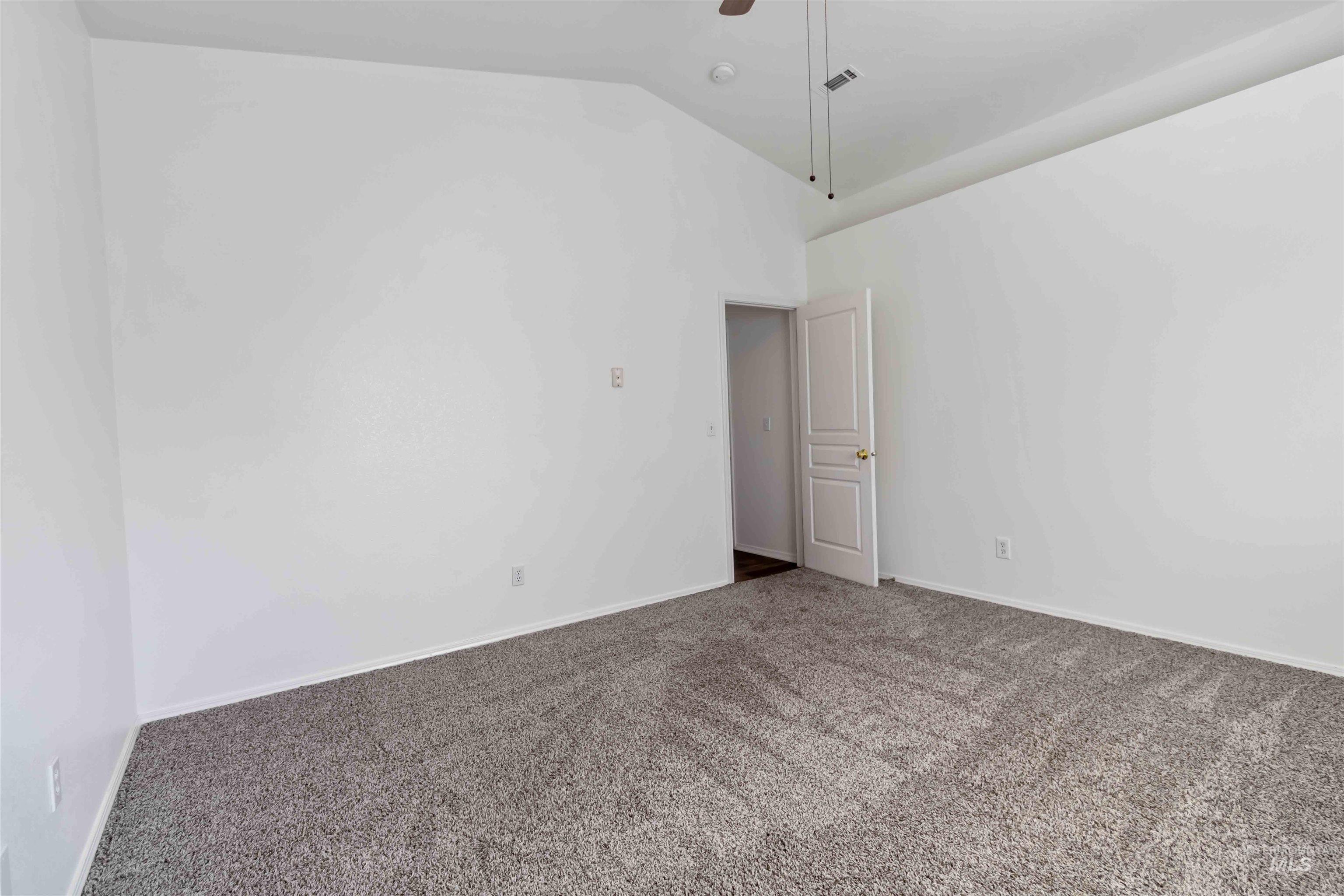 Carpeted empty room with ceiling fan and high vaulted ceiling