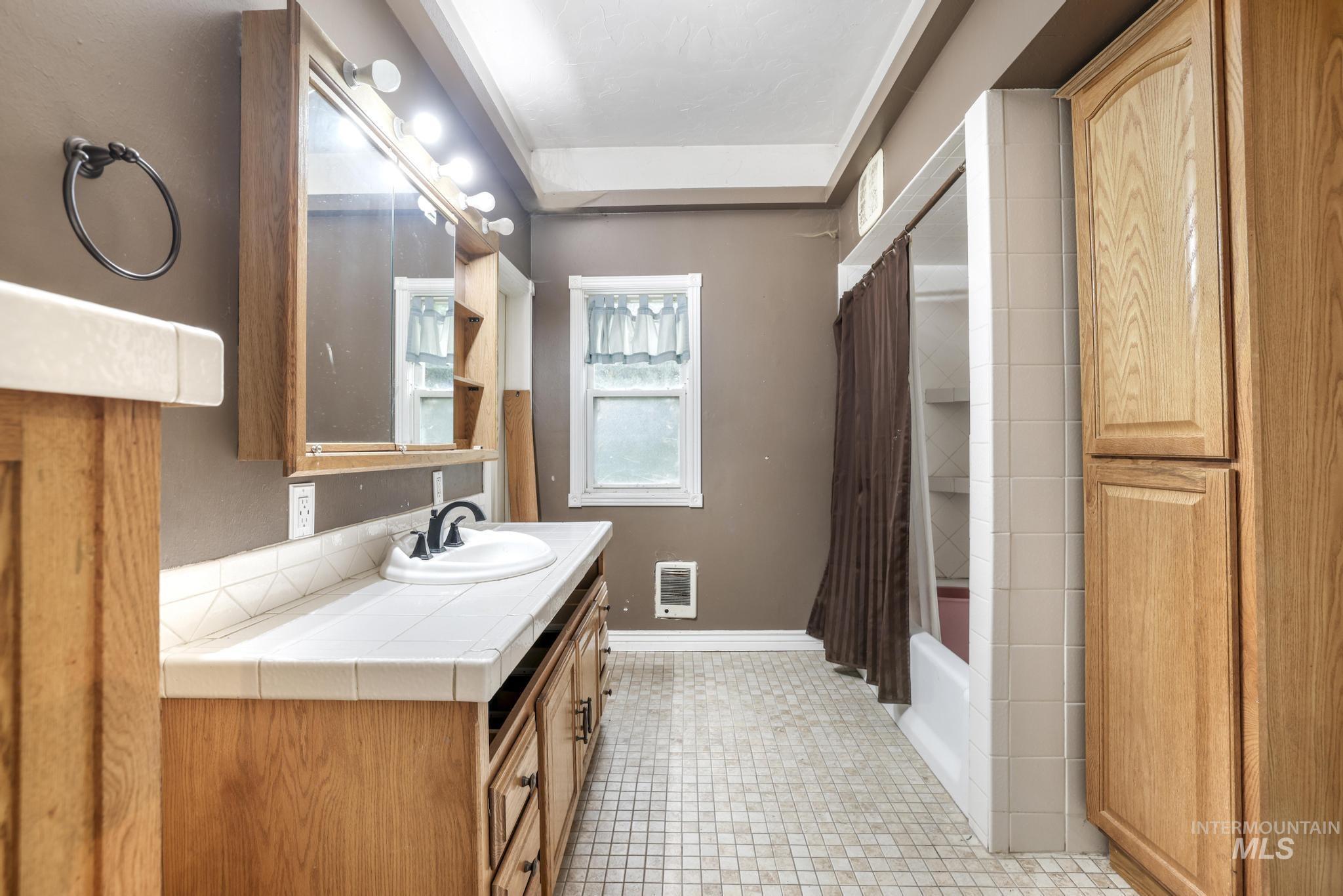 Bathroom featuring shower / bath combination with curtain, vanity, and heating unit