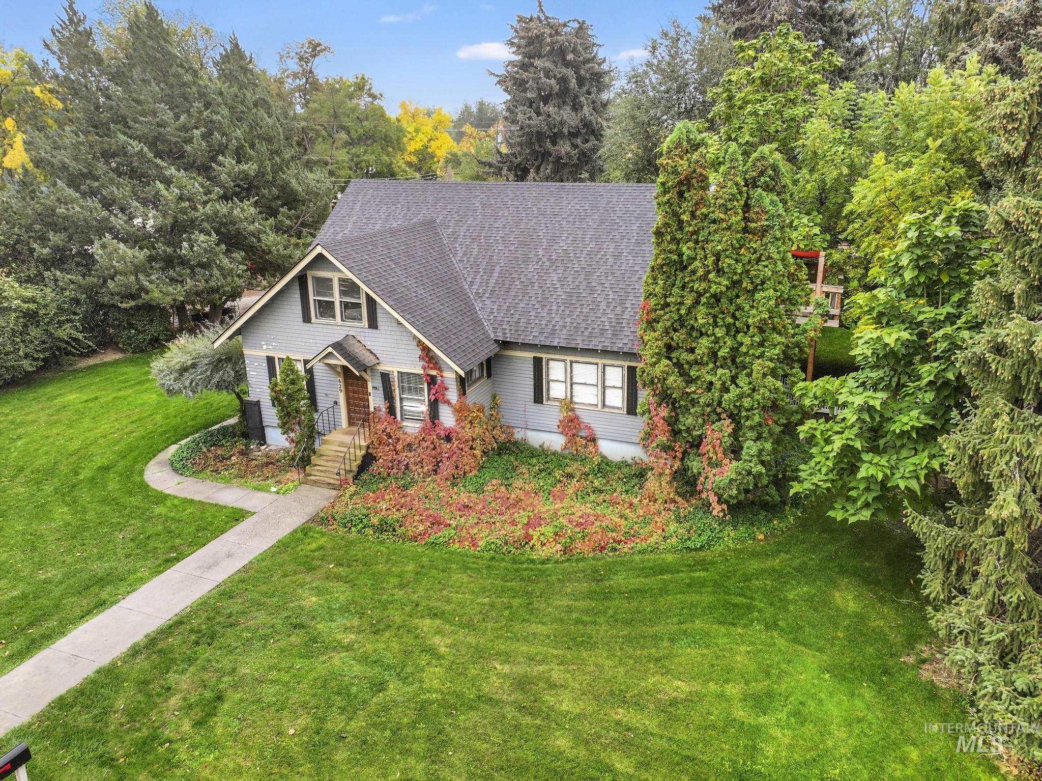 View of front of home with a front yard, roof with shingles, and view of wooded area