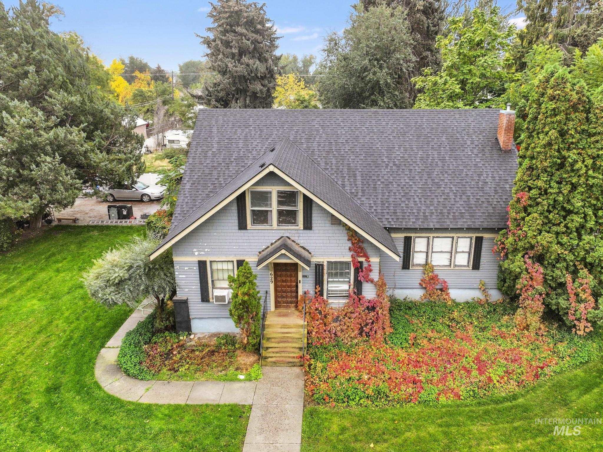 View of front of property featuring a front yard, a chimney, and roof with shingles