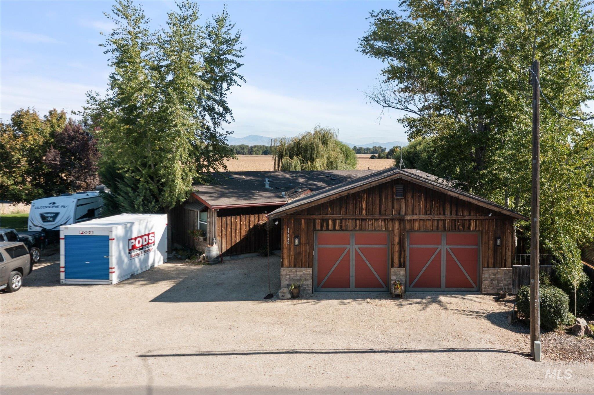 View of front of home featuring stone siding, a garage, and an outbuilding