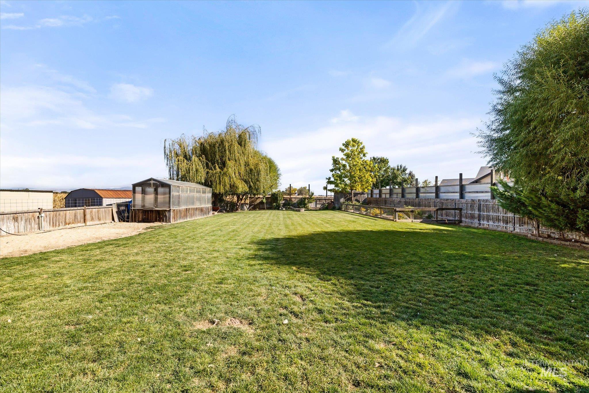 Fenced backyard with a greenhouse and an outdoor structure