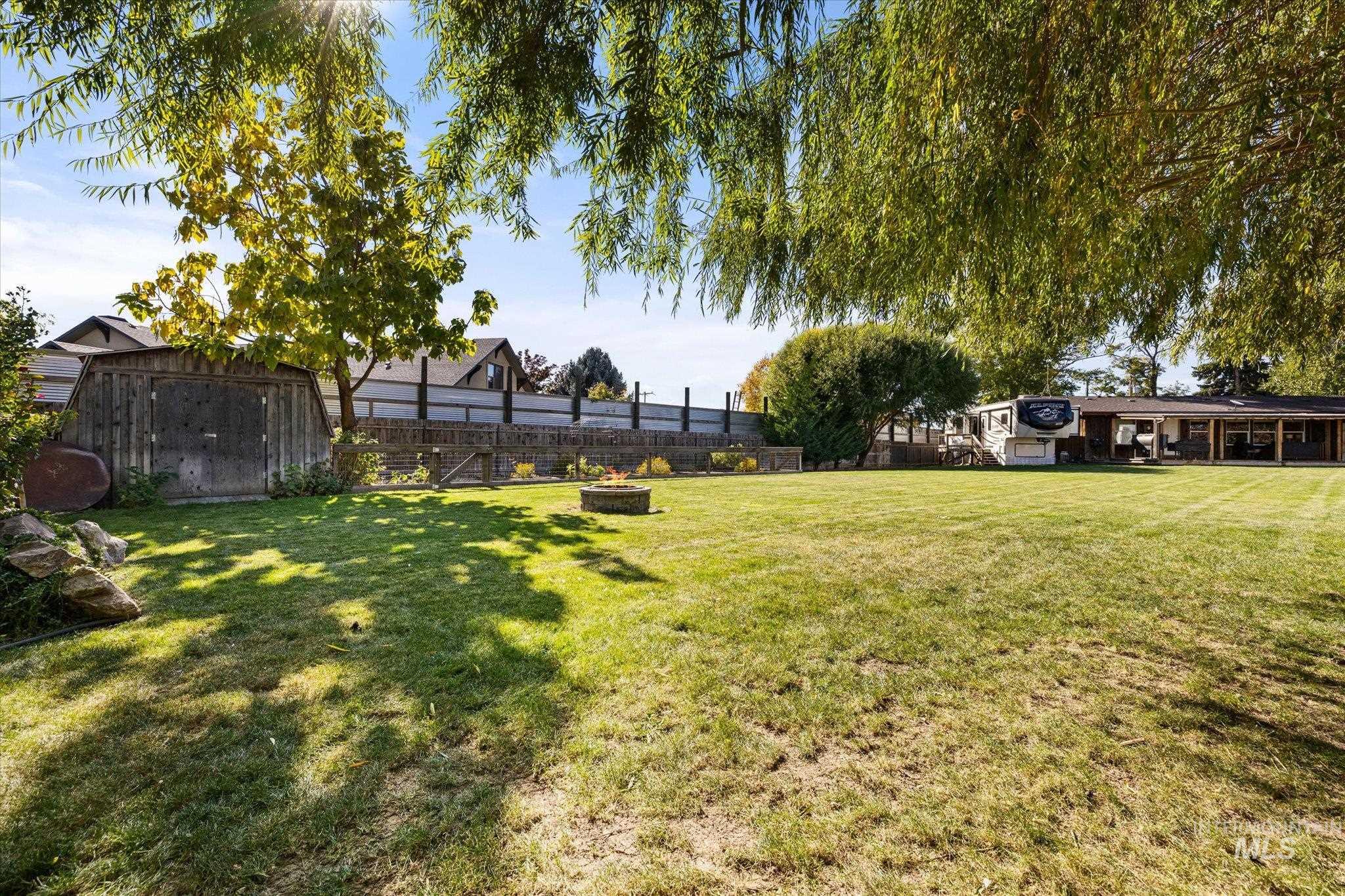Fenced backyard featuring a storage shed and an outdoor fire pit