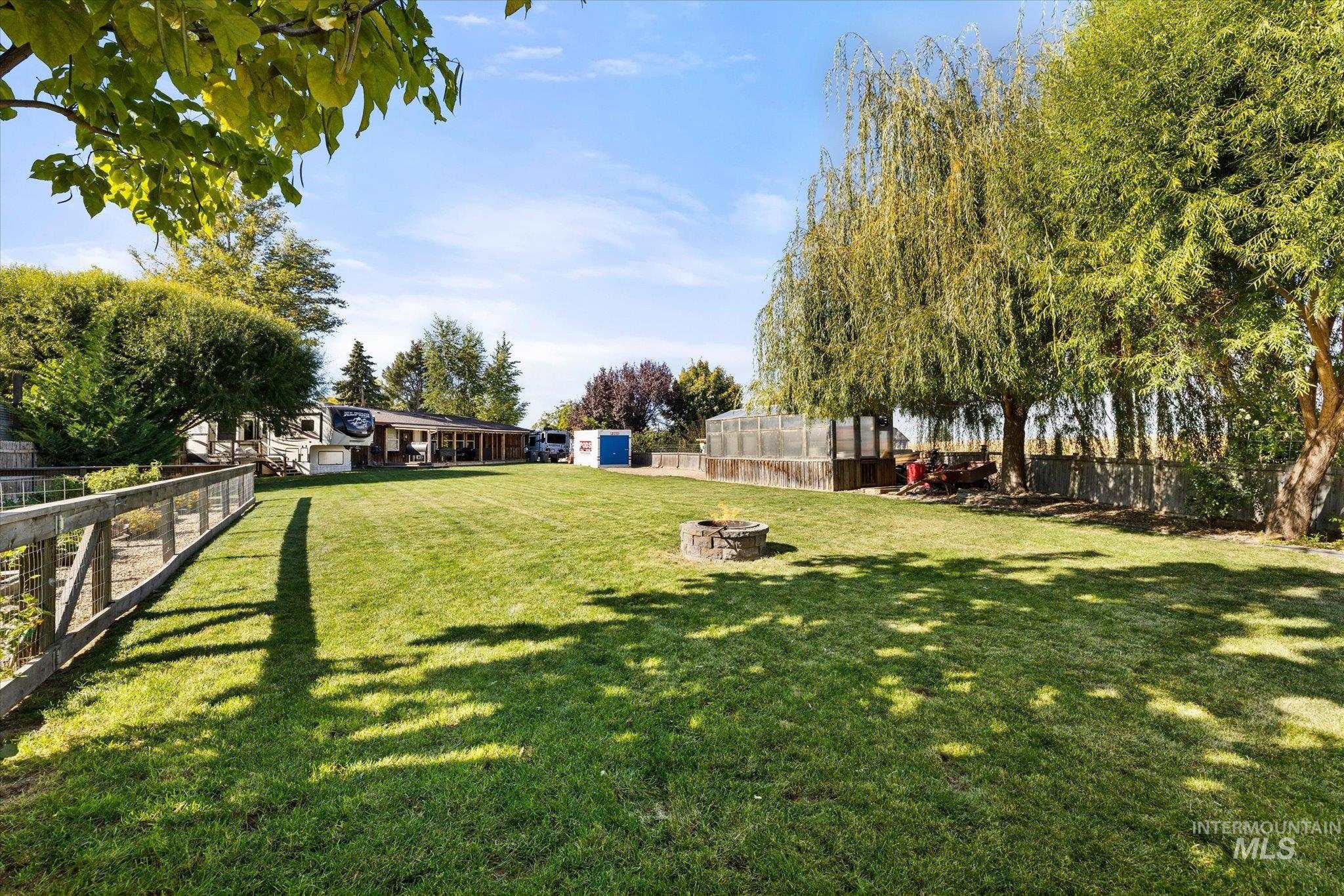 Fenced backyard featuring an outdoor structure and a fire pit