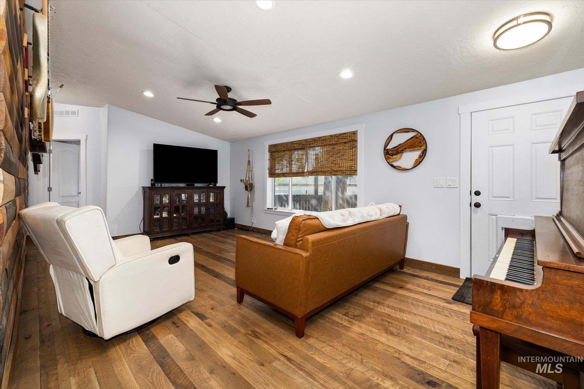 Living area with hardwood / wood-style flooring, recessed lighting, vaulted ceiling, and ceiling fan
