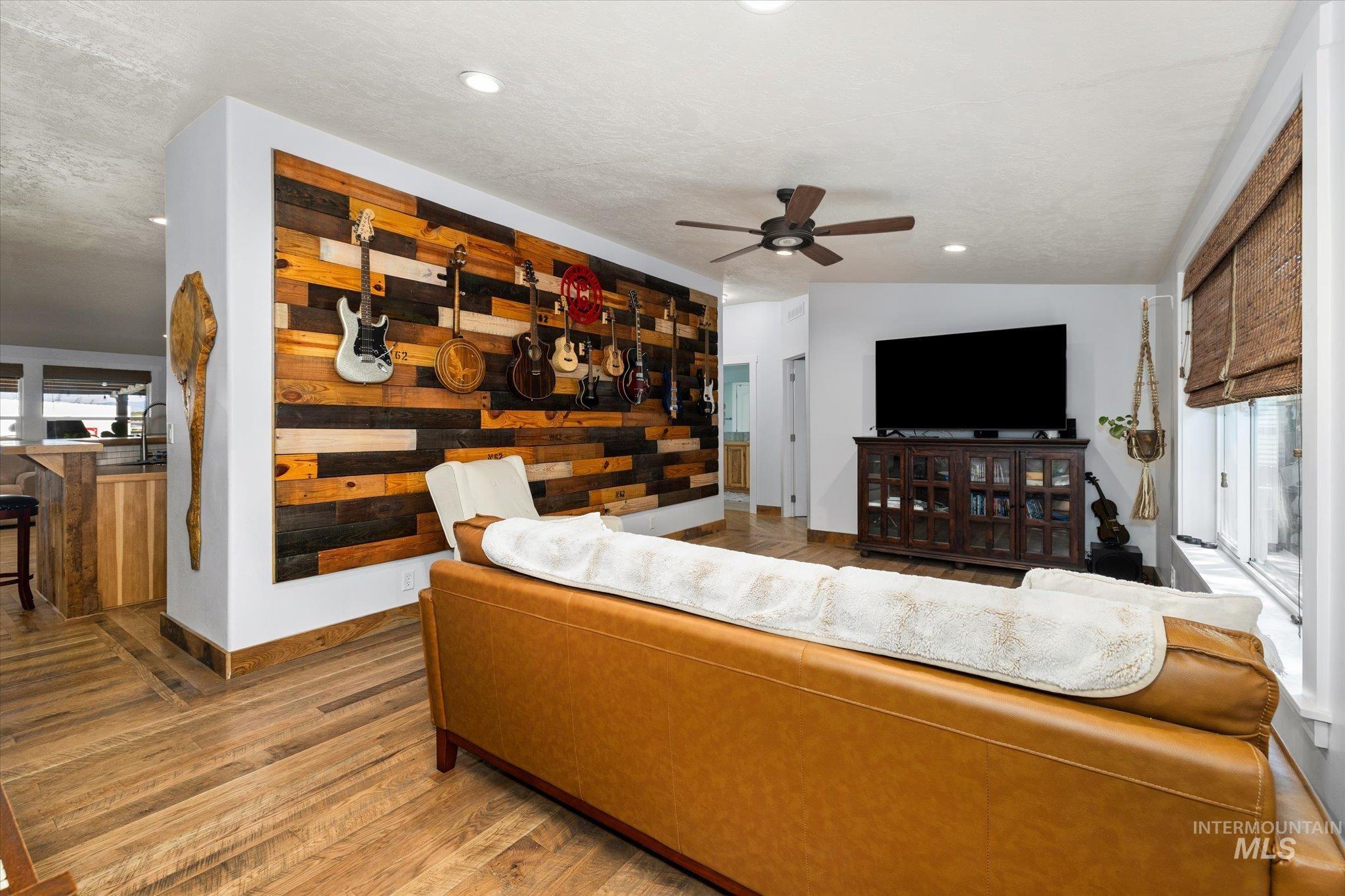 Living room with healthy amount of natural light, wood finished floors, a ceiling fan, vaulted ceiling, and recessed lighting