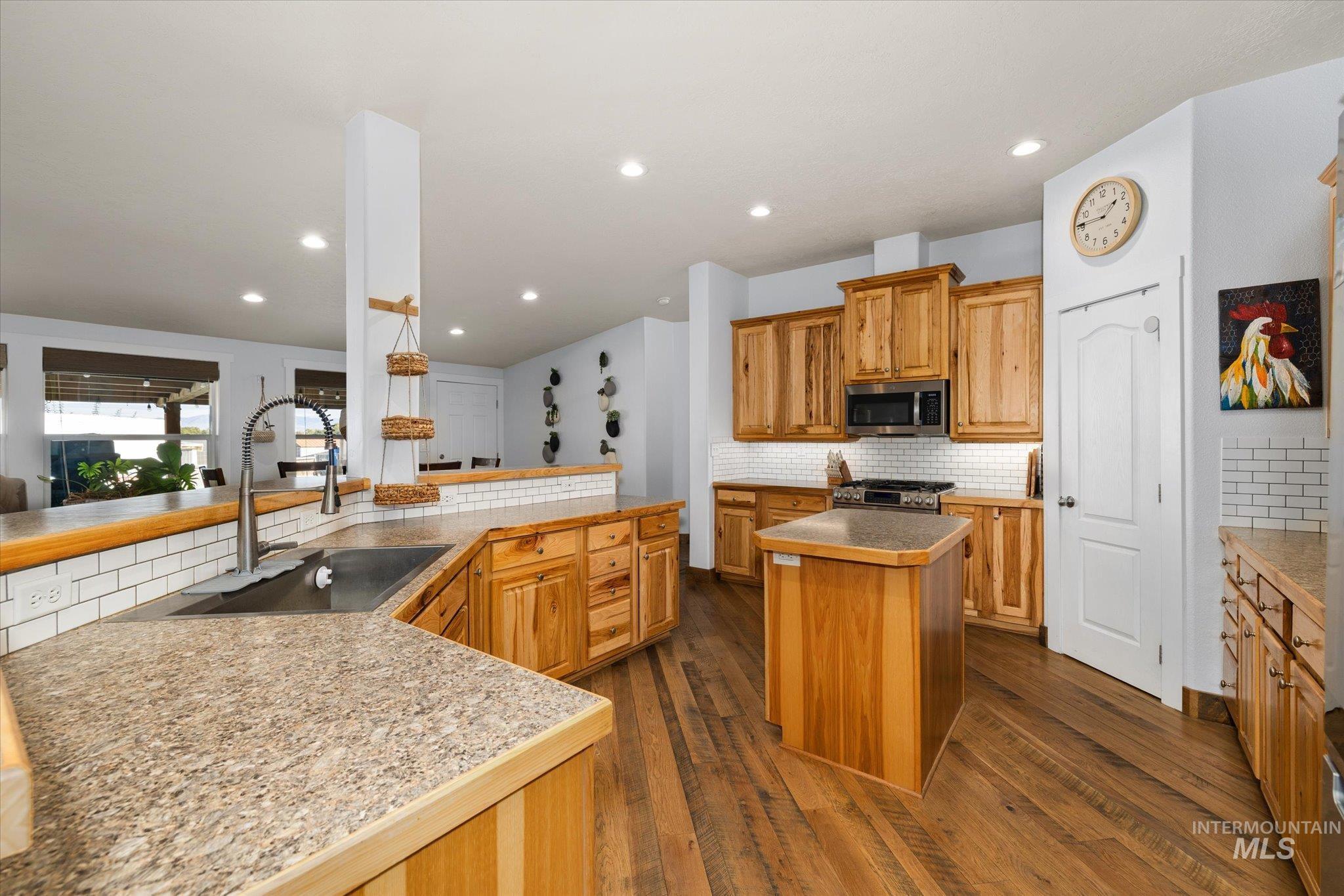 Kitchen featuring a kitchen island, decorative backsplash, brown cabinets, dark wood finished floors, and recessed lighting