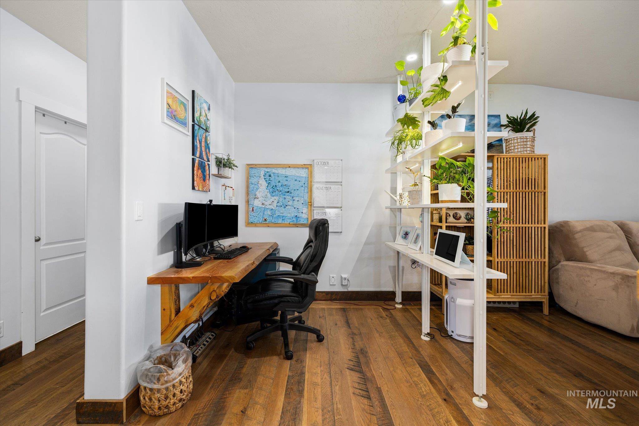 Home office featuring dark wood-style floors and vaulted ceiling
