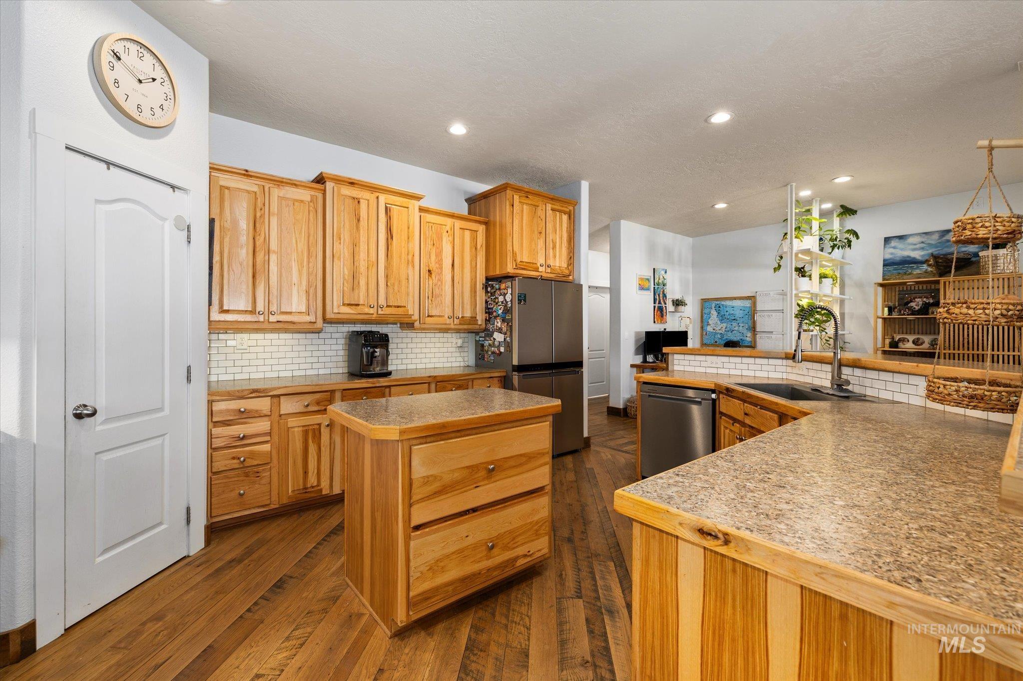 Kitchen featuring tasteful backsplash, light countertops, stainless steel appliances, dark wood-type flooring, and recessed lighting