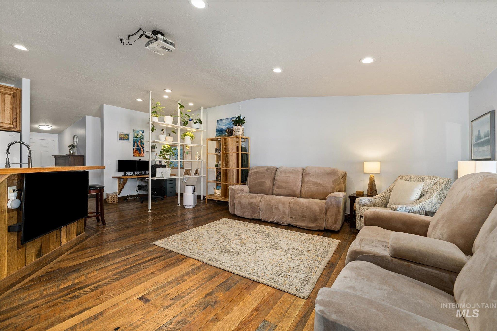 Living area with dark wood finished floors, lofted ceiling, and recessed lighting